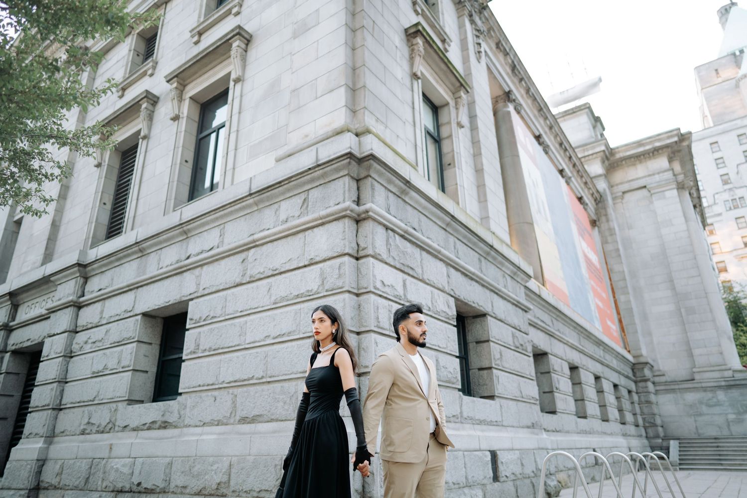 Elegant couple poses on grand marble staircase of historic building during wedding photoshoot.