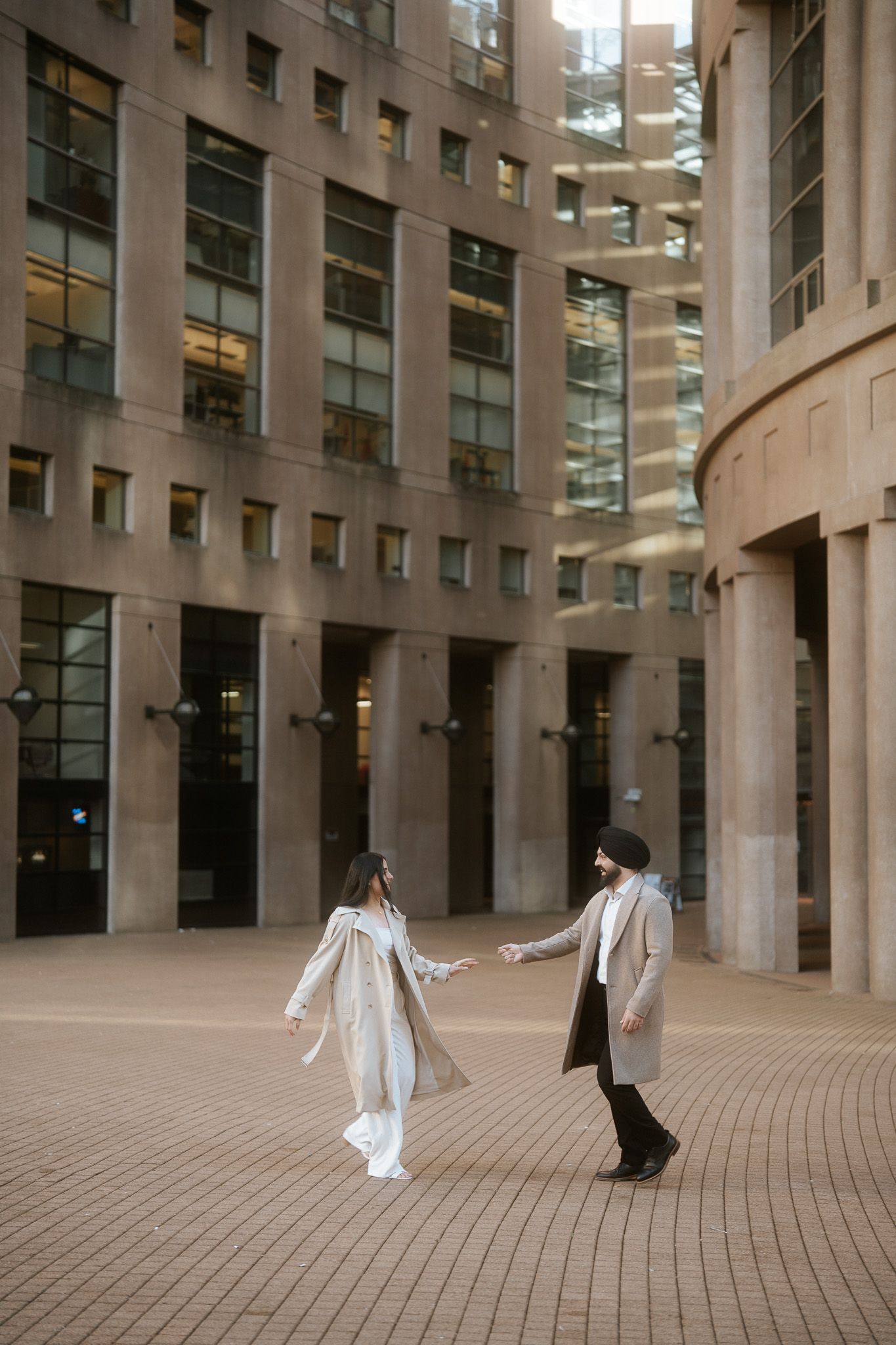 Two dancers perform an elegant duet among curved stone columns in a modern architectural space.