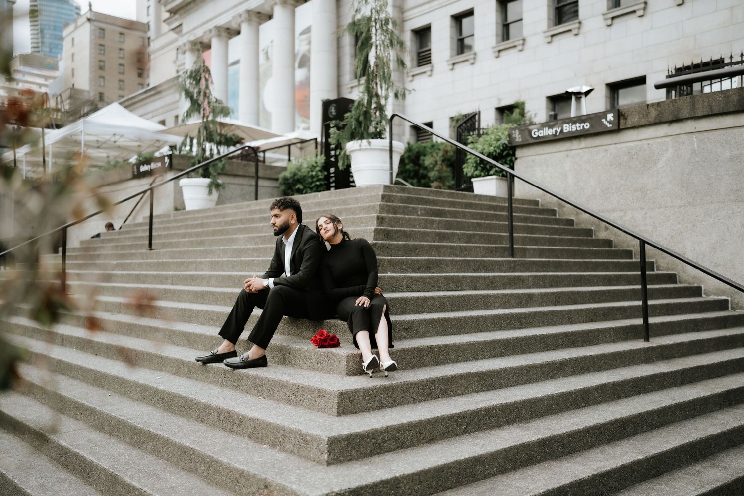 Couple poses on grand stone steps of historic building.