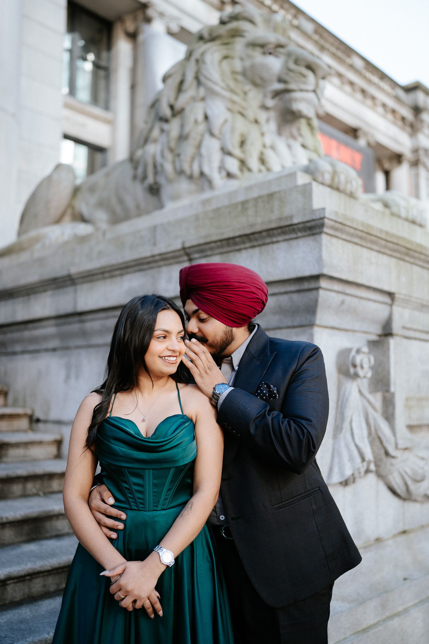 A romantic moment shared between a couple on elegant stone steps, with one wearing a dark red turban.