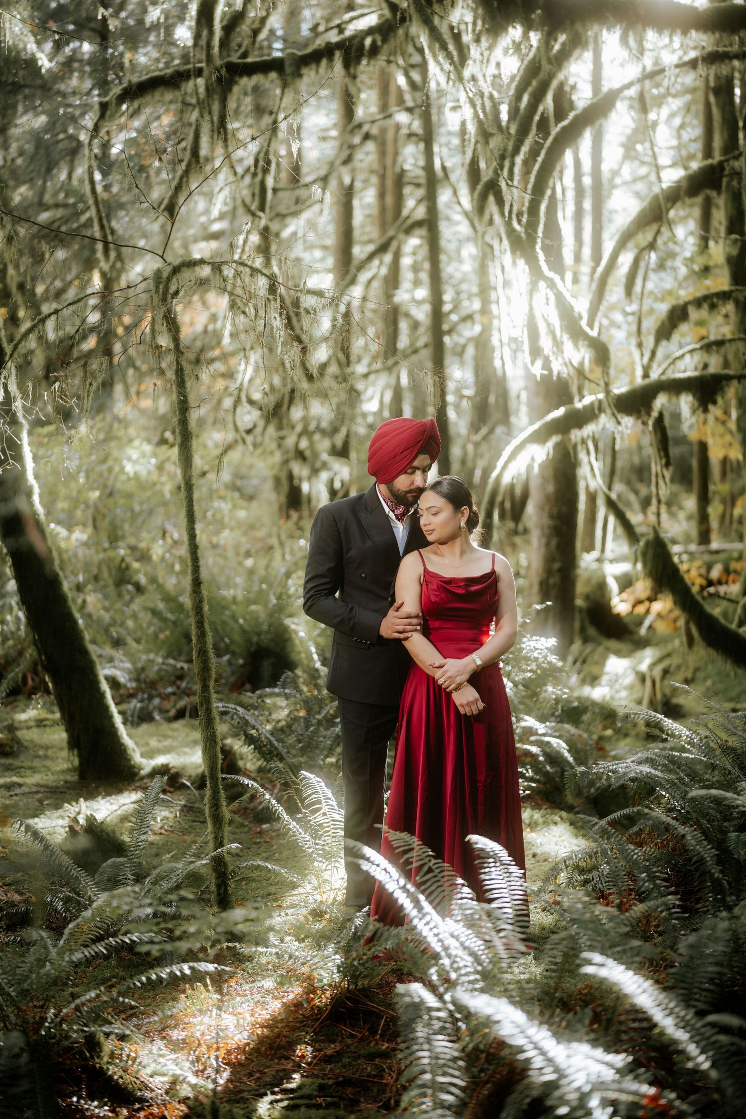 Dreamy forest engagement photos with sunbeams filtering through tall trees.