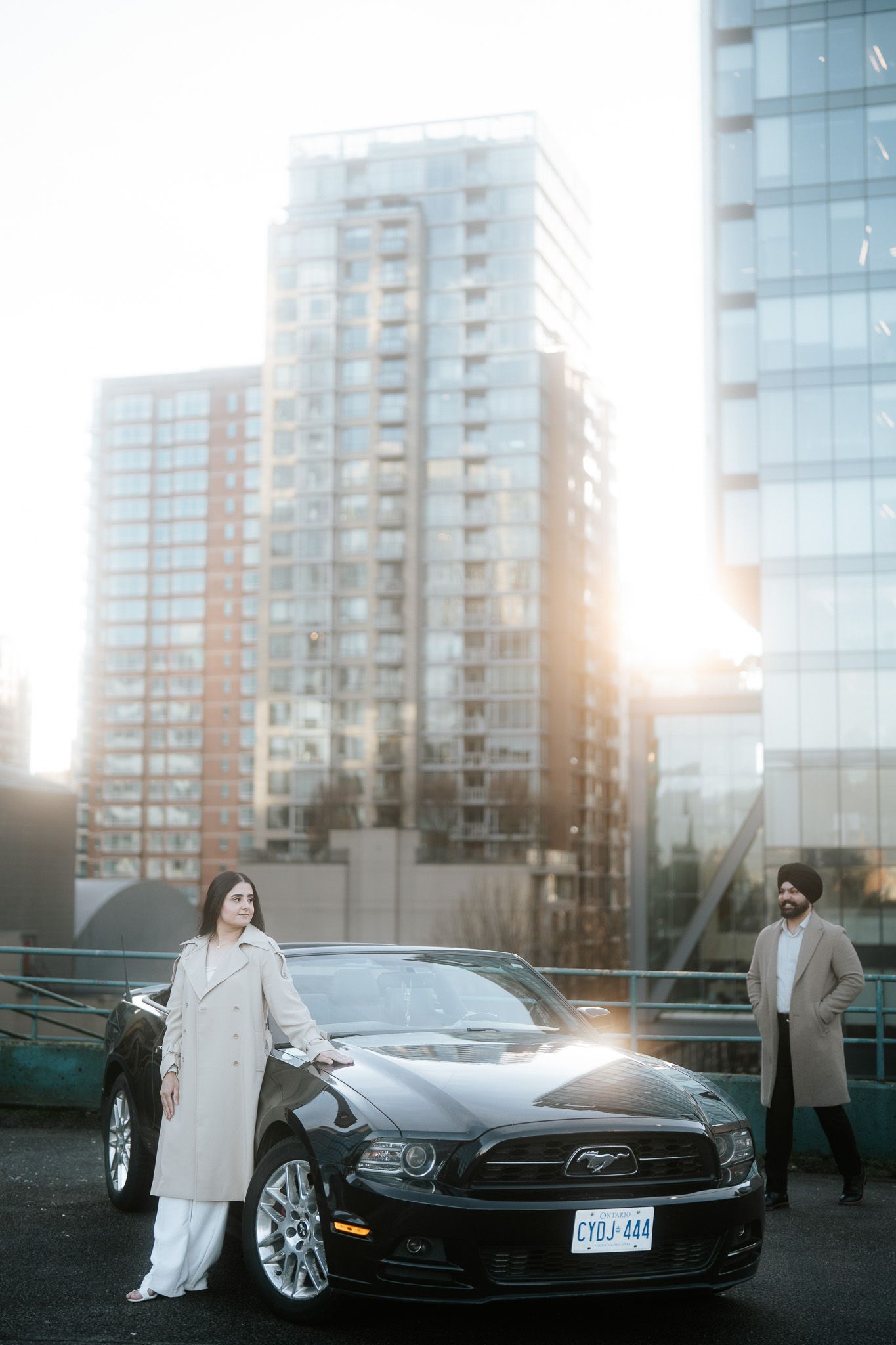 Luxury Tesla Model S parked in front of modern glass high-rise buildings during sunset.