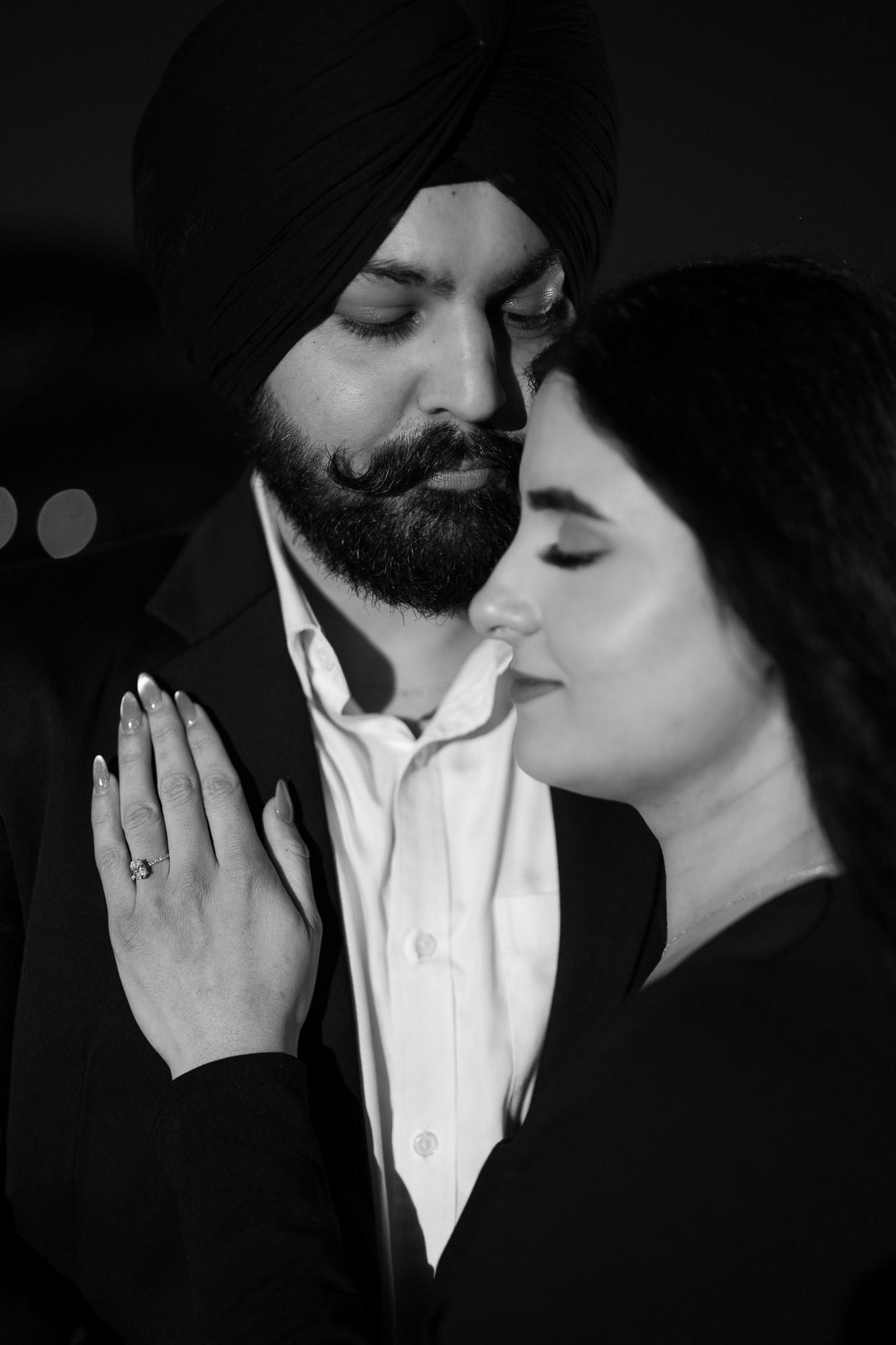 Intimate black and white portrait showing a tender romantic moment between a couple, with one wearing a turban.