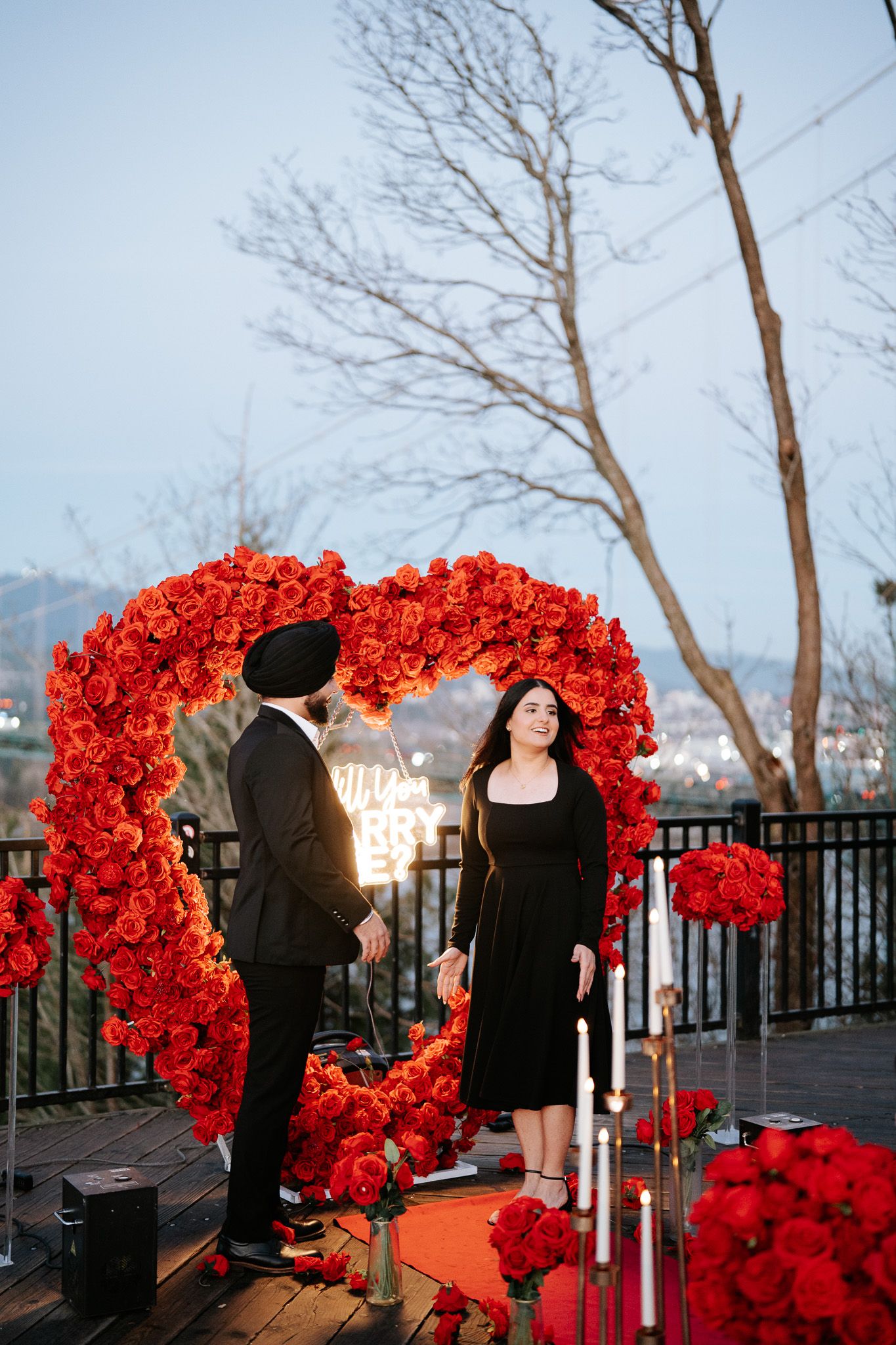 A romantic proposal scene with a stunning red rose arch against a winter sky backdrop.