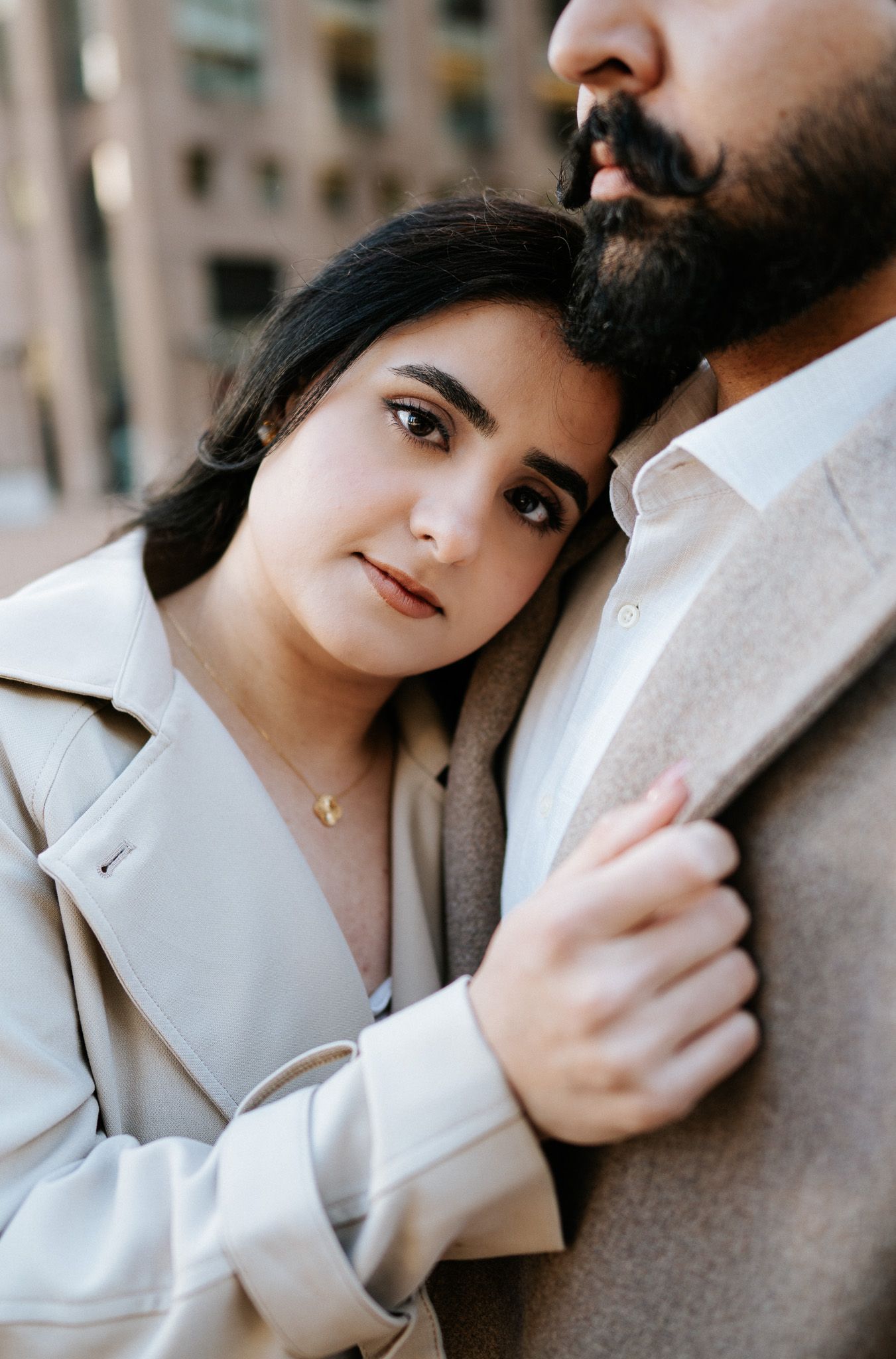 A romantic couple in neutral tones embraces in a series of intimate poses against an urban backdrop.