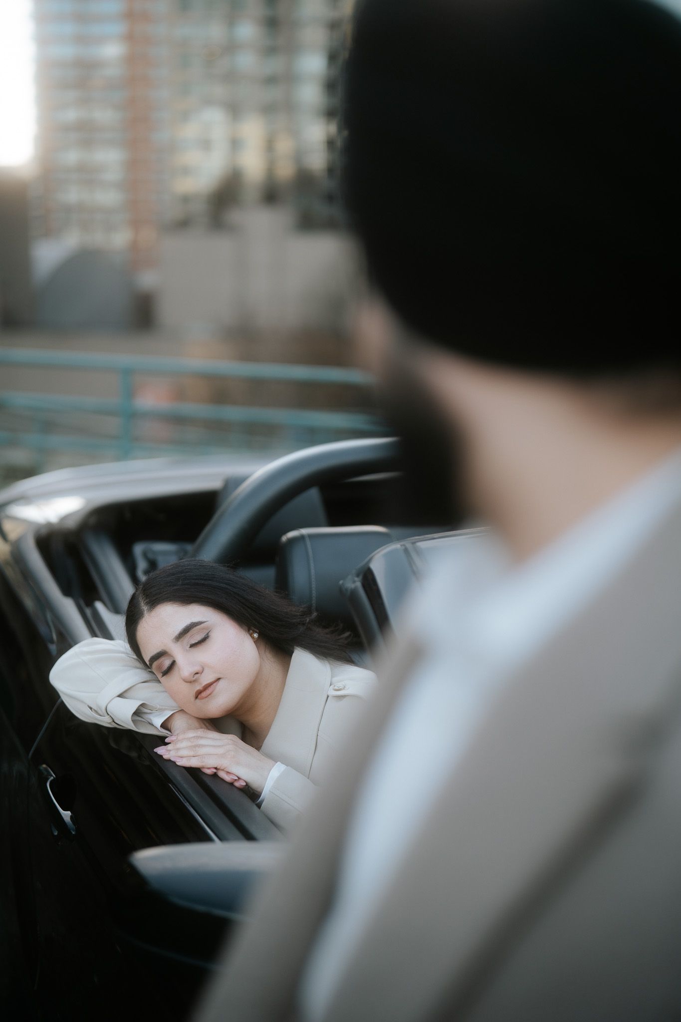 A person sleeps peacefully in the backseat of a car while someone sits in the driver's seat in the foreground.