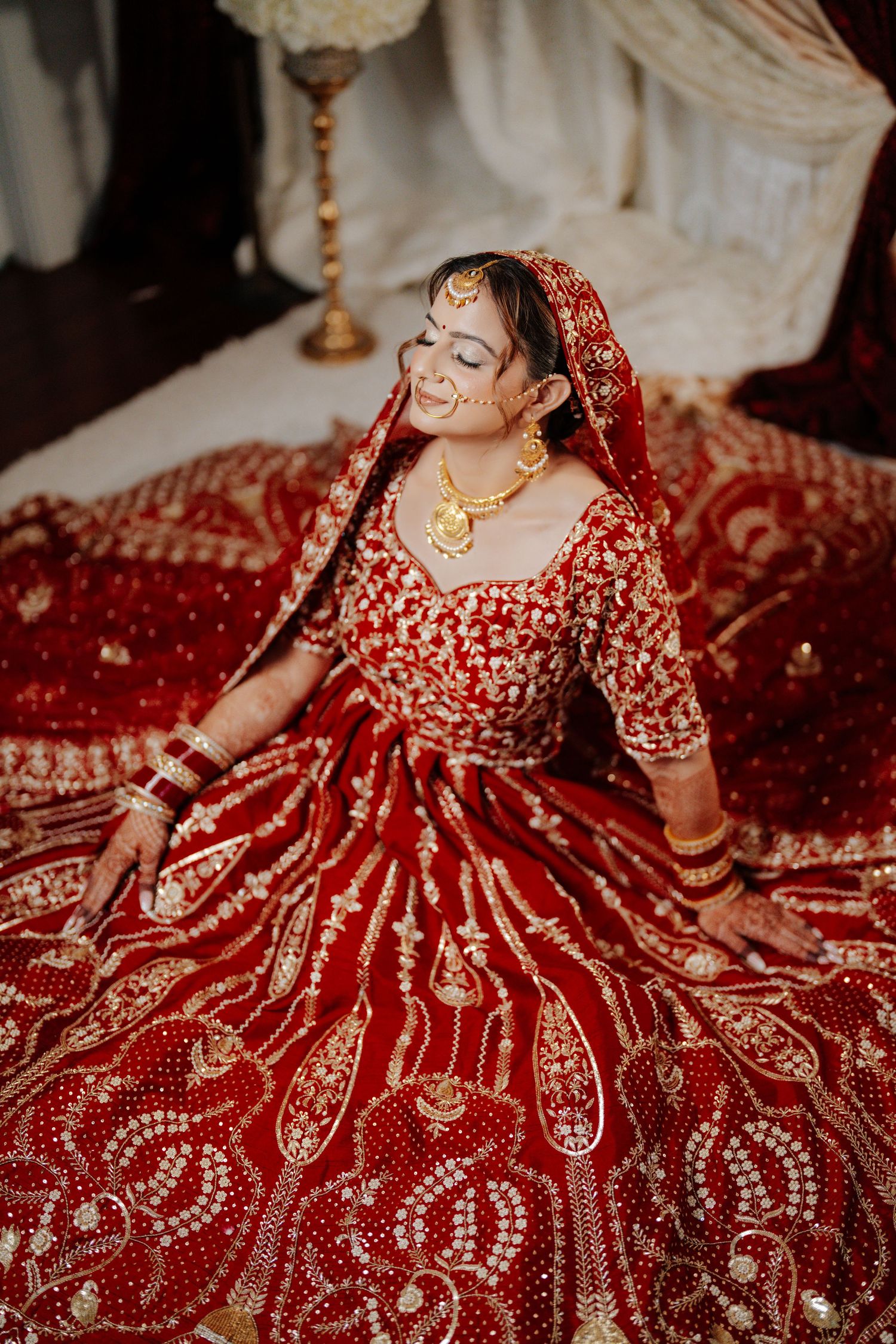 Stunning red and gold embroidered Indian bridal lehenga with intricate traditional designs spread out on display.