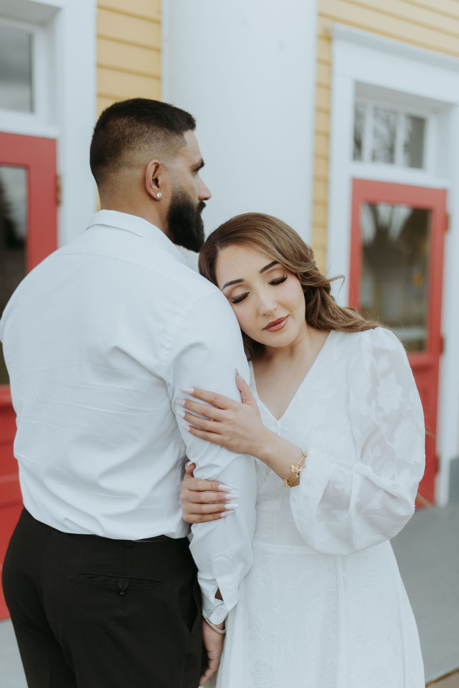 A couple in matching white outfits embrace during a photo session.