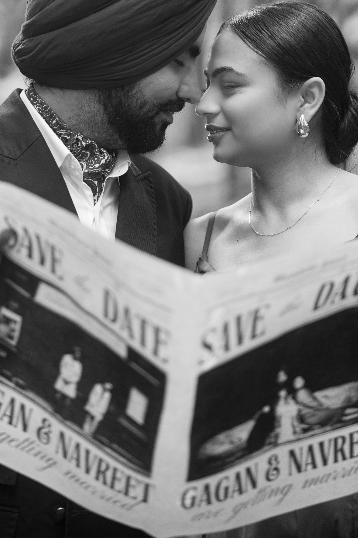 Black and white close-up of couple reading newspaper during forest engagement session.