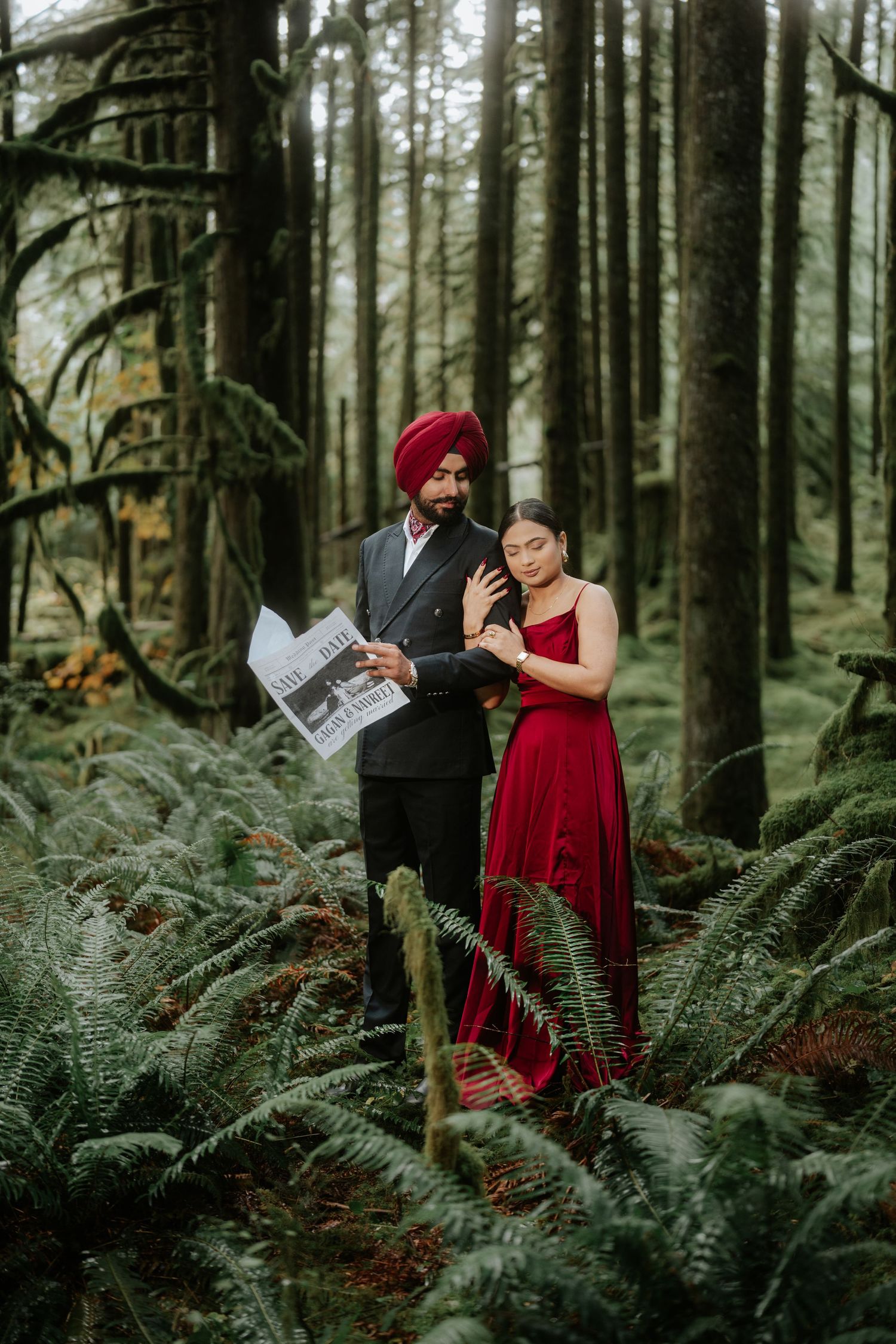 Couple reading newspapers during a forest photoshoot among tall evergreen trees.