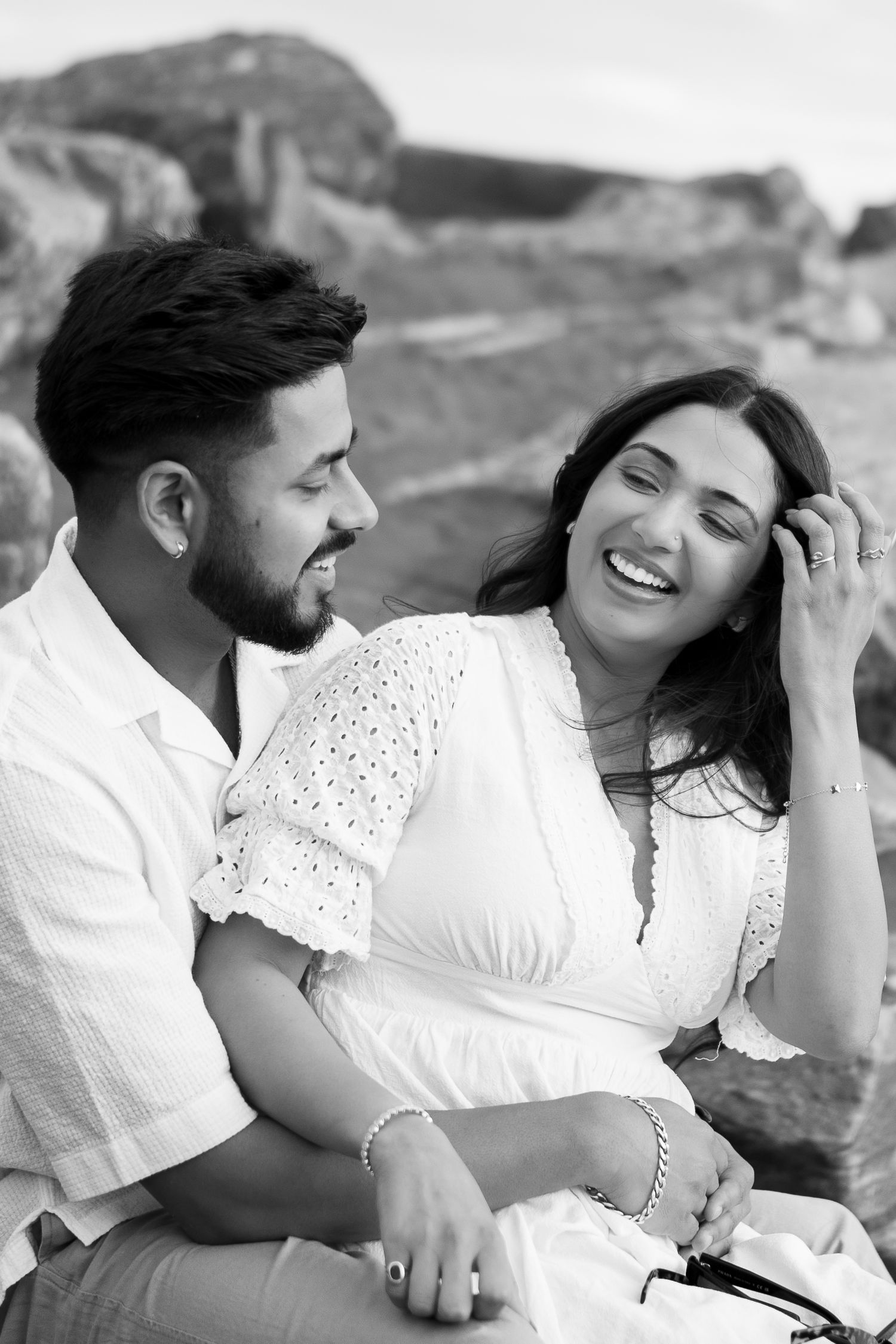 Candid black and white photo of couple laughing together outdoors.