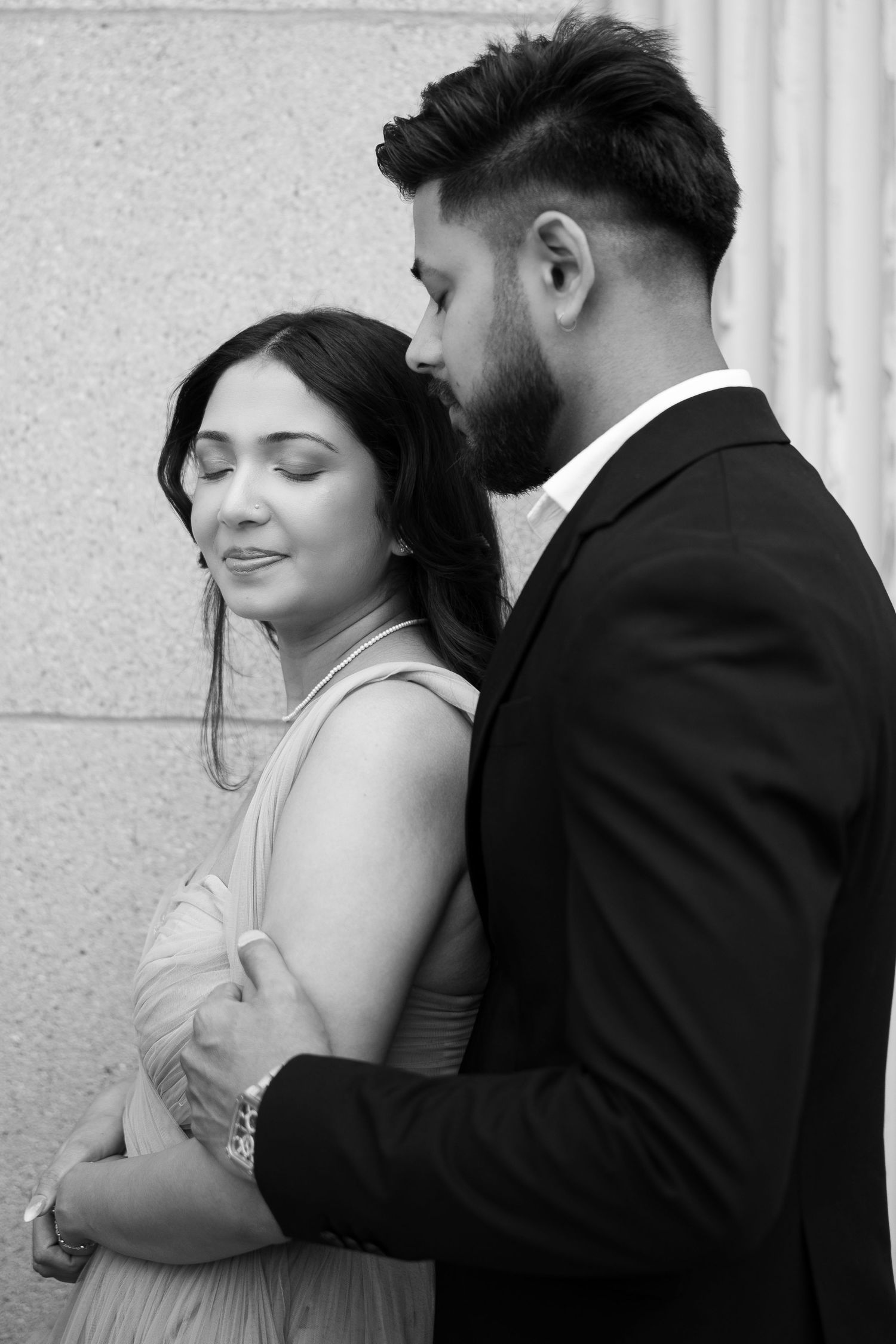 An intimate black and white portrait against a textured wall.
