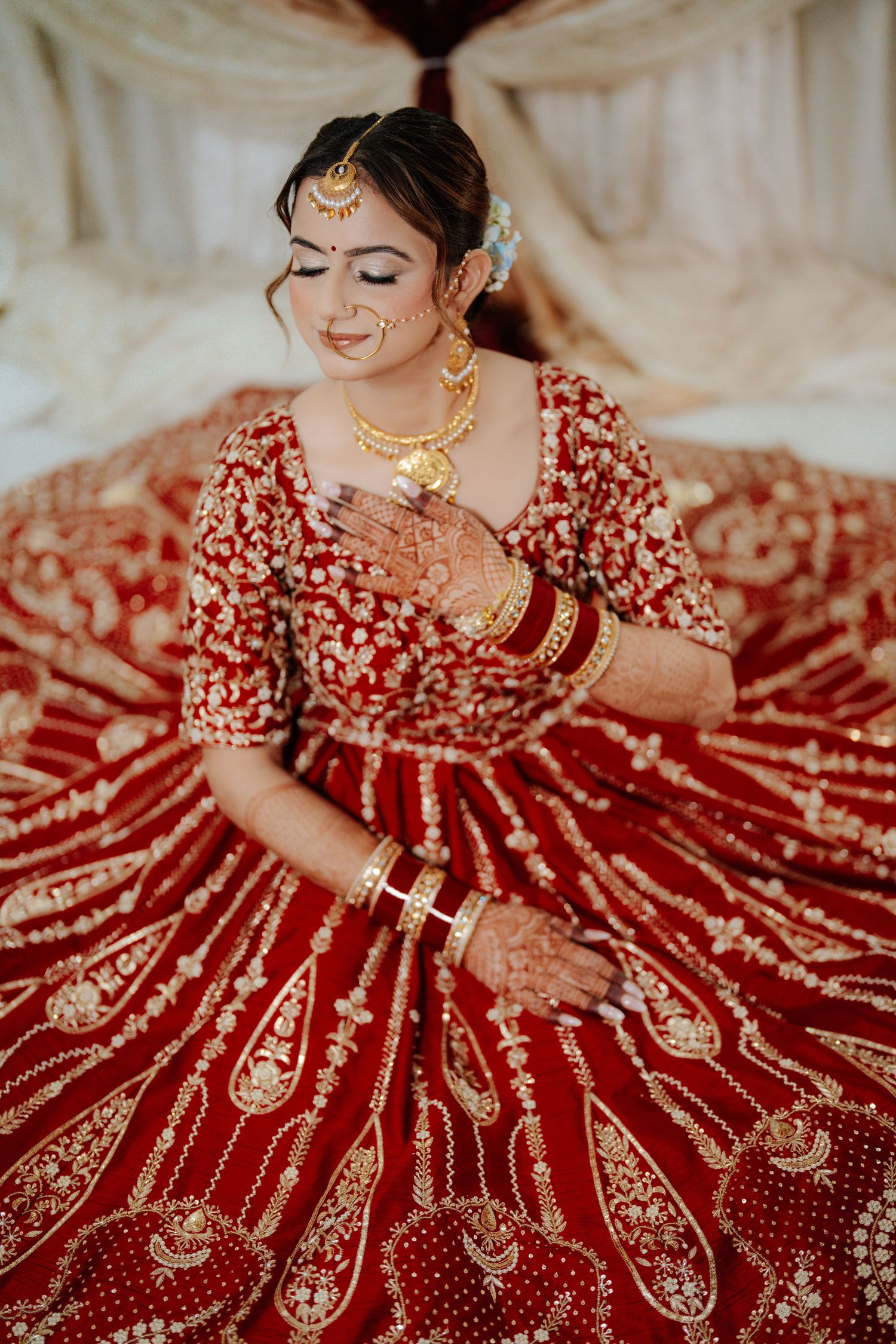 Ornate red bridal lehenga with gold embroidery displayed in artistic poses showing intricate details.
