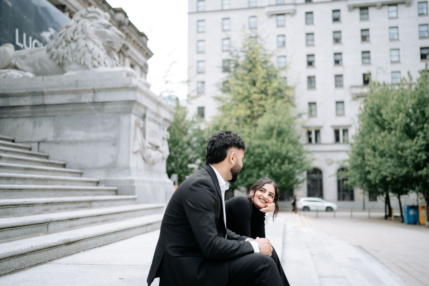 A couple poses for romantic photos near stone steps and urban architecture.