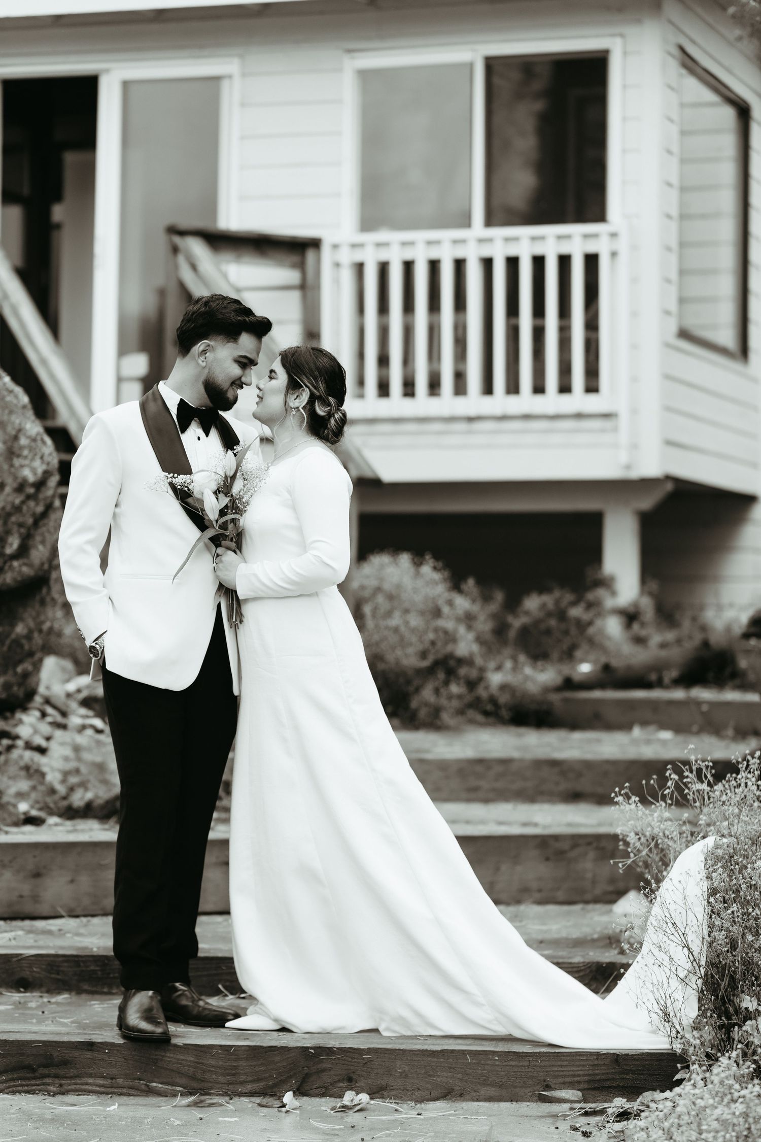 Black and white romantic wedding sequence shows couple sharing intimate moments in front of a white house.