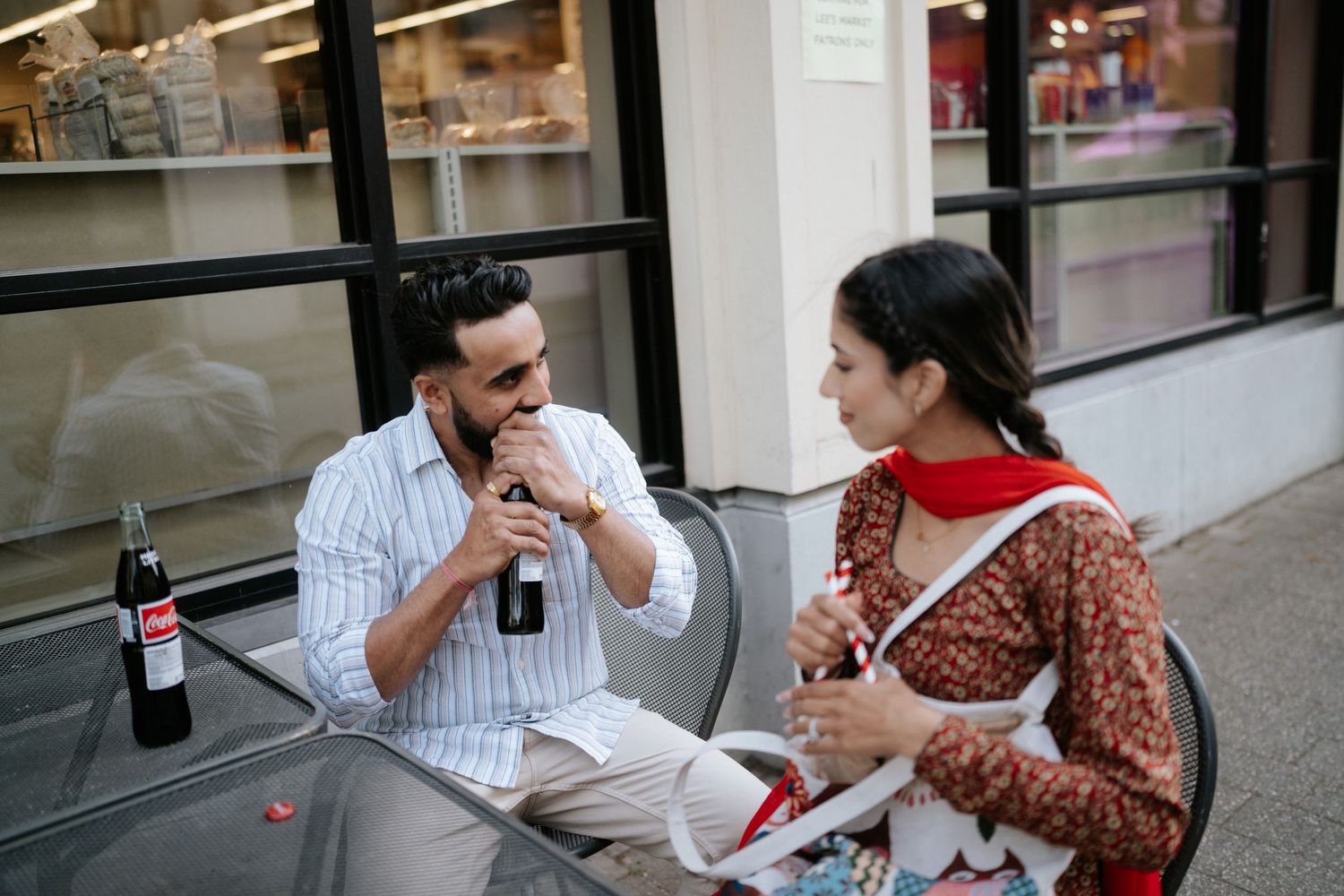 A couple enjoys wine and conversation at an outdoor cafe table on a sunny afternoon.