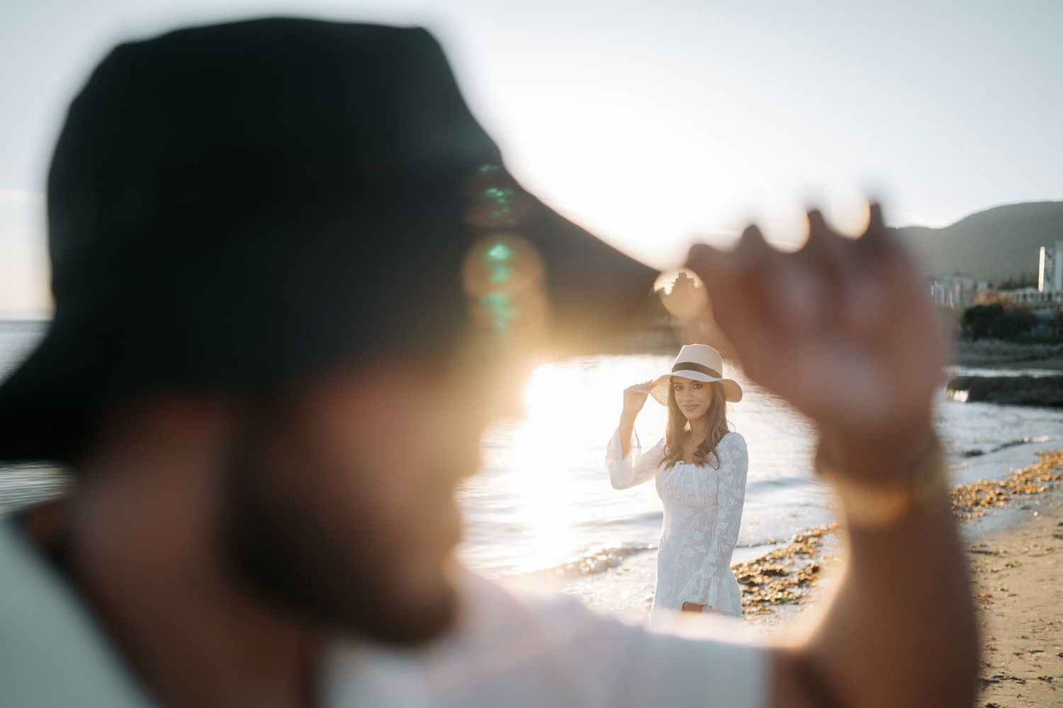 Silhouetted figures on a beach at sunset with lens flare creating a dreamy atmospheric effect.