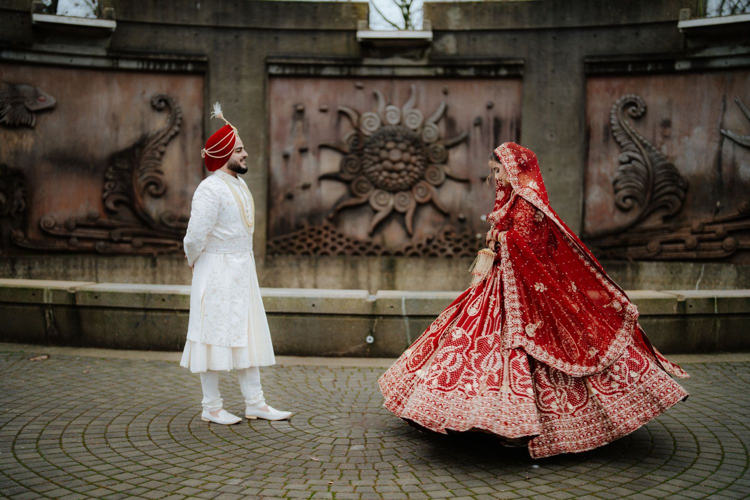 Panoramic view of a traditional Indian wedding couple against stone wall backdrop.