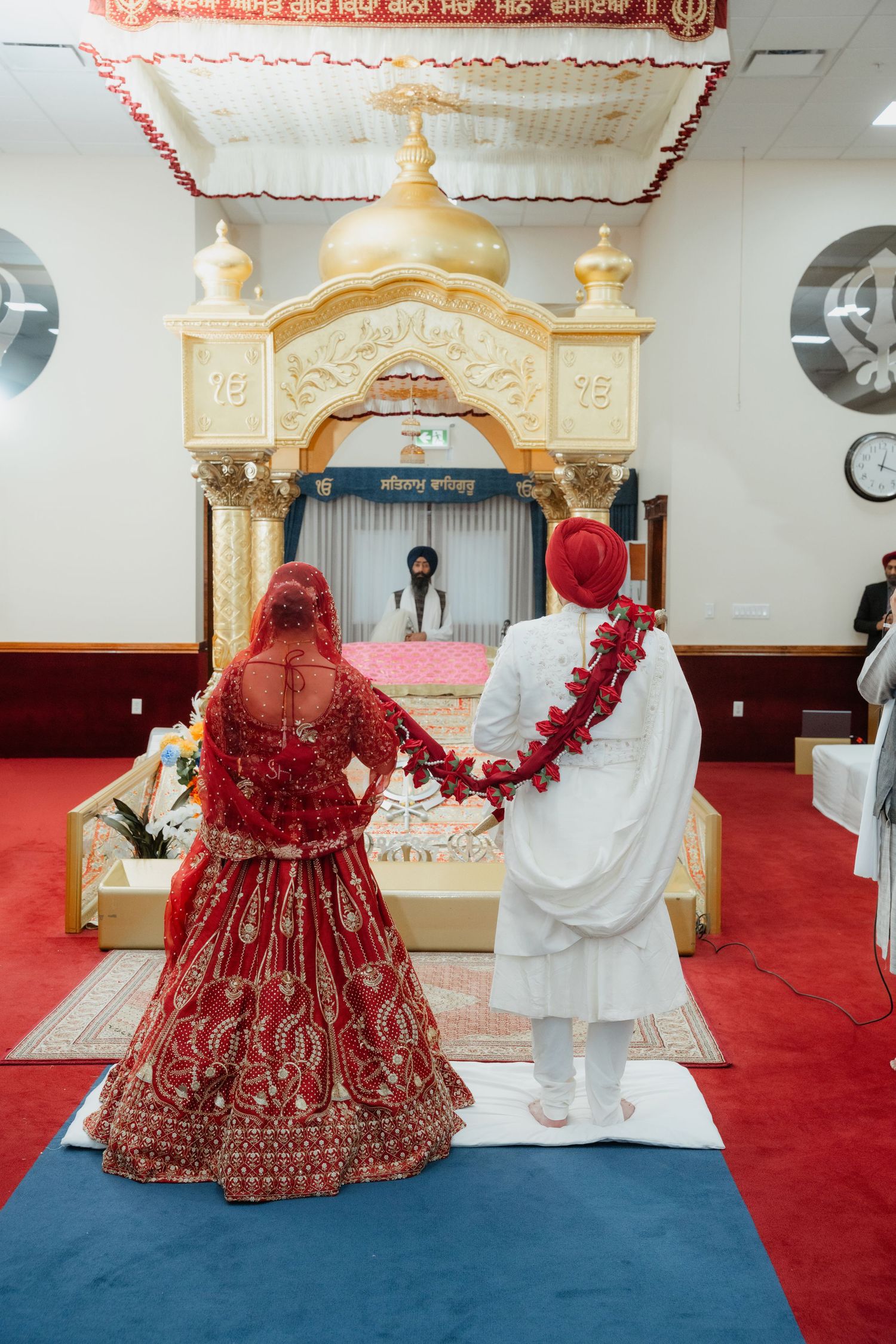 Wedding ceremony in temple setting with ornate gold altar and red carpet.
