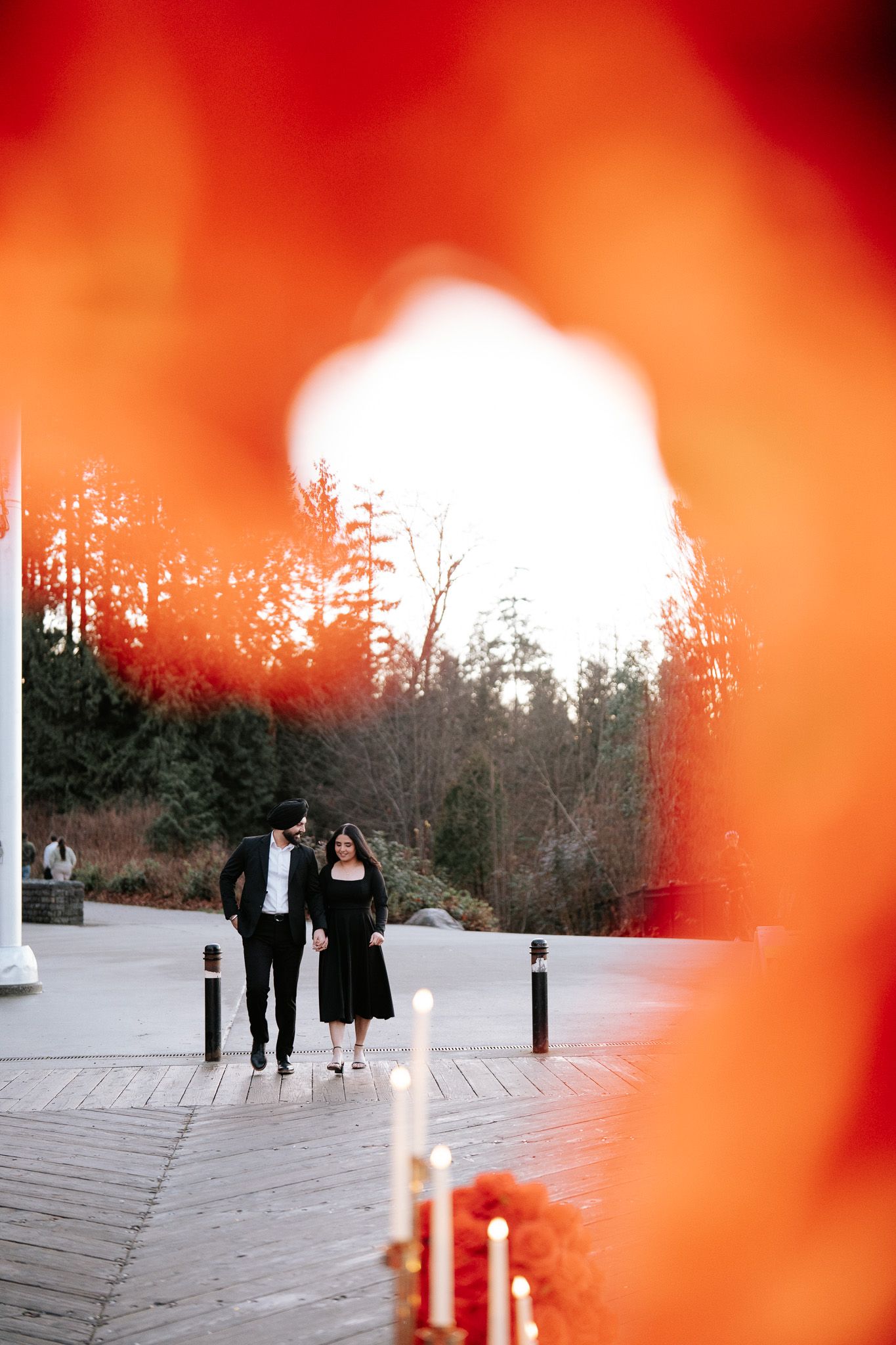 People walking on a path with a vibrant red-orange bokeh effect in the foreground.