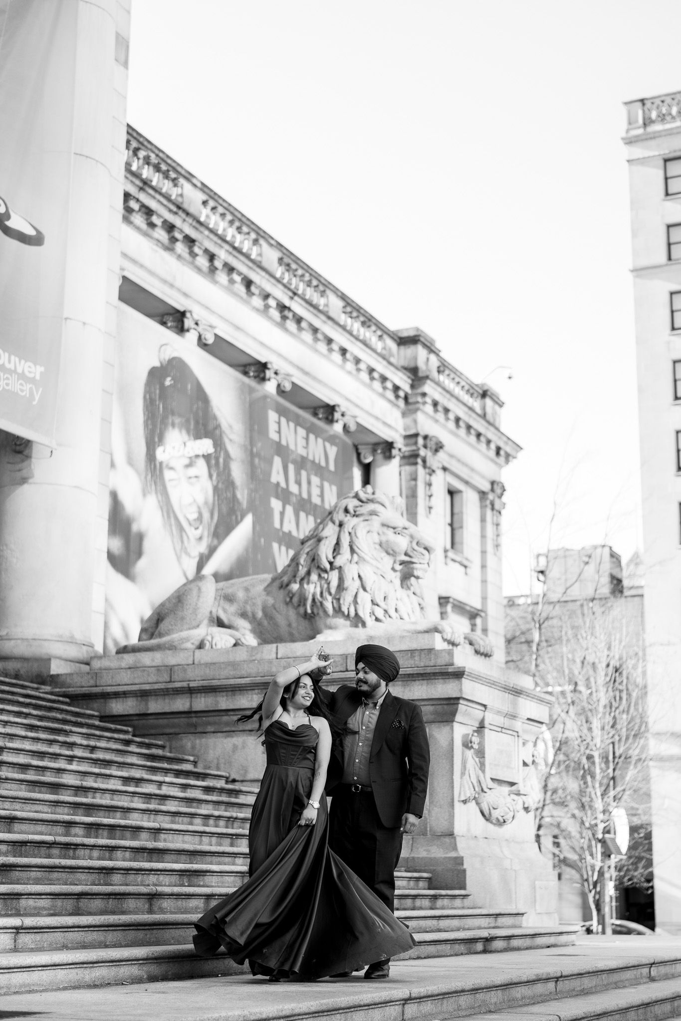 A romantic black and white photo series of a couple sitting on stone steps in an elegant architectural setting.