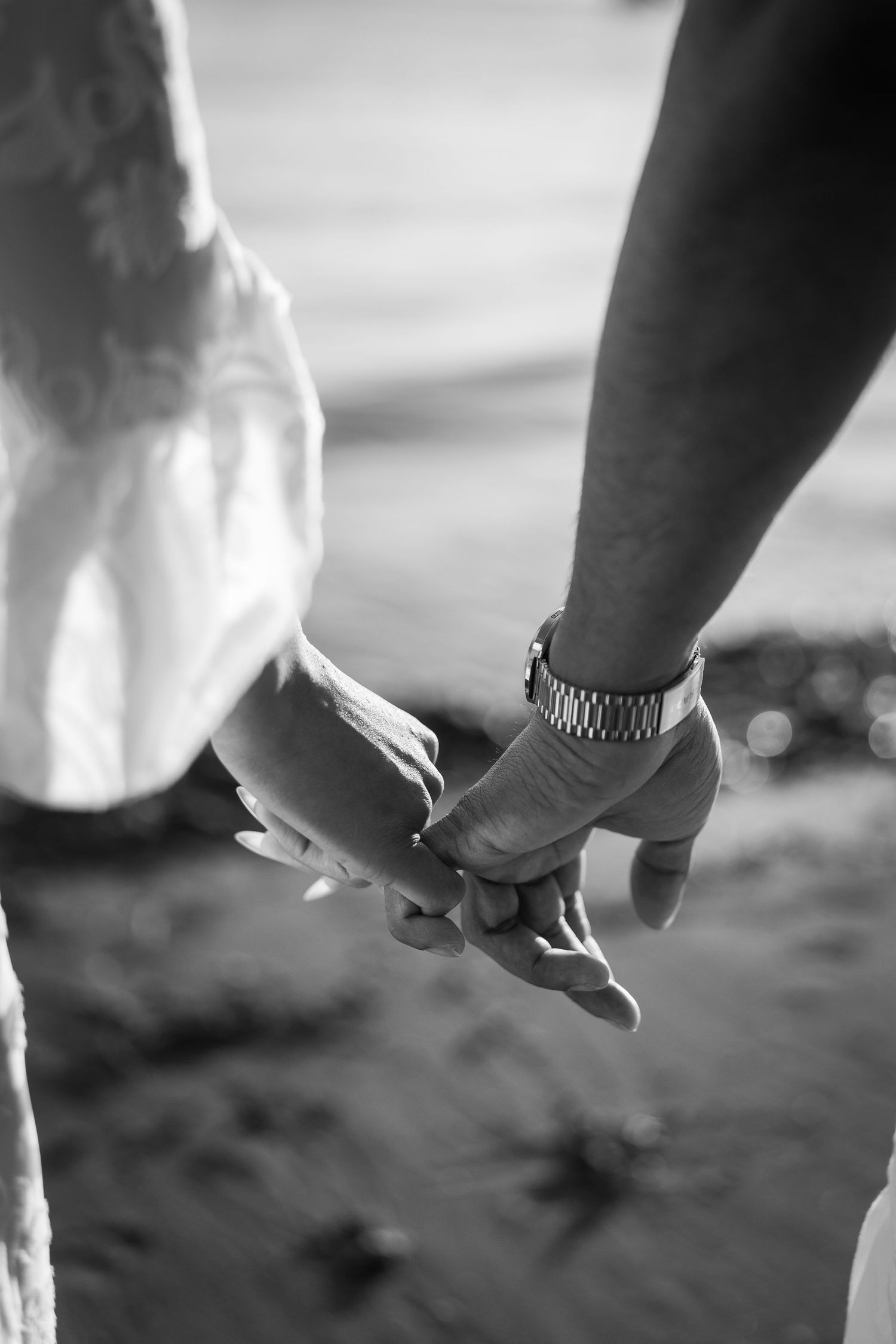 Black and white photo of two hands reaching towards each other against a blurred background.