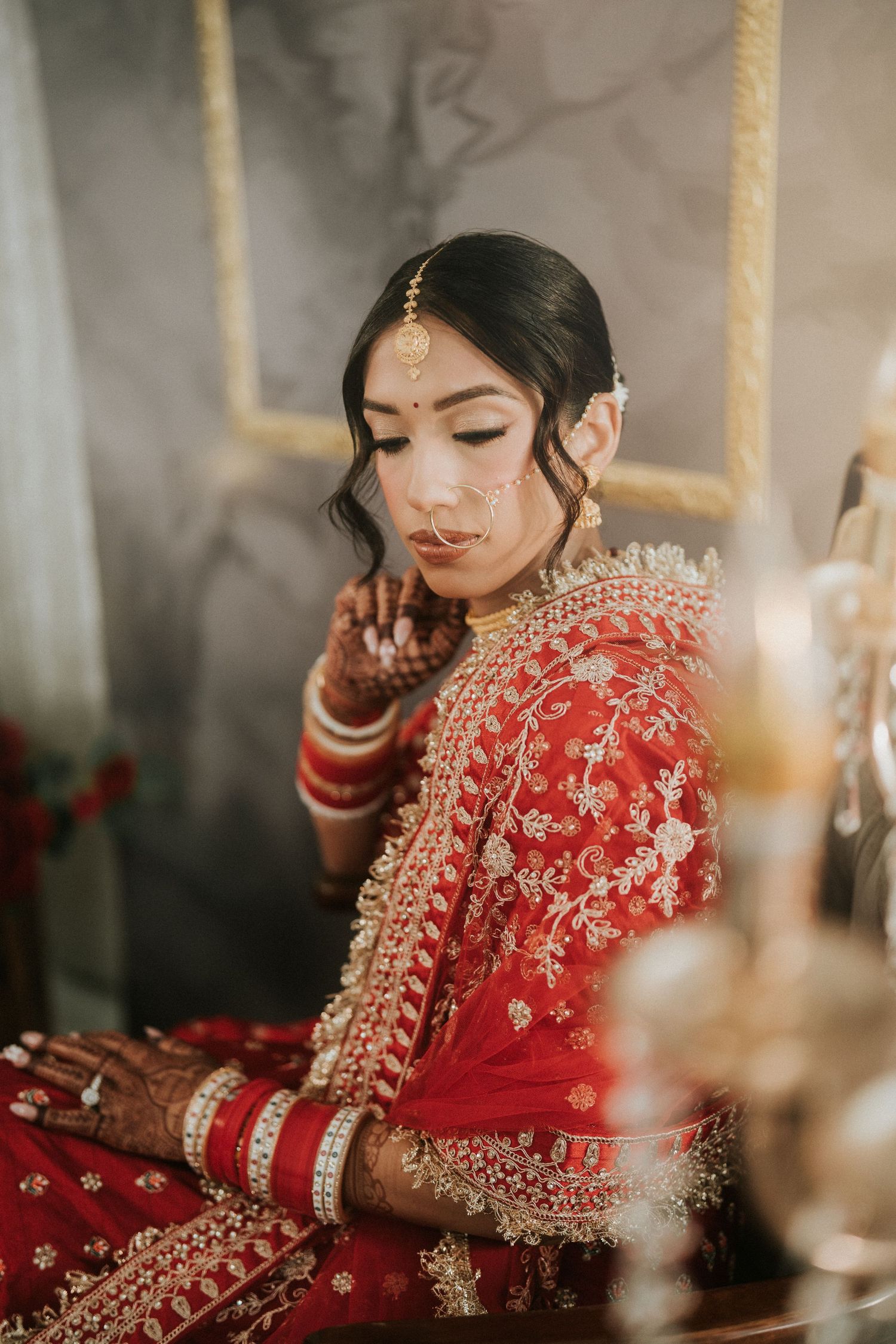 Close-up shots of bride in red embroidered lehenga with traditional jewelry and makeup.