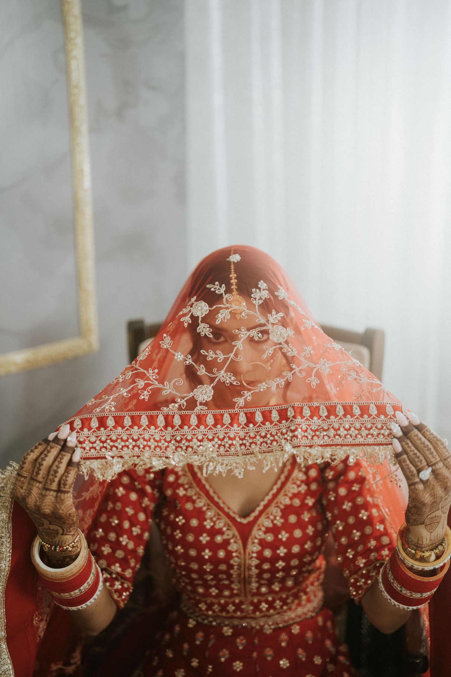 Detailed view of intricate embroidery and embellishments on a red bridal lehenga.