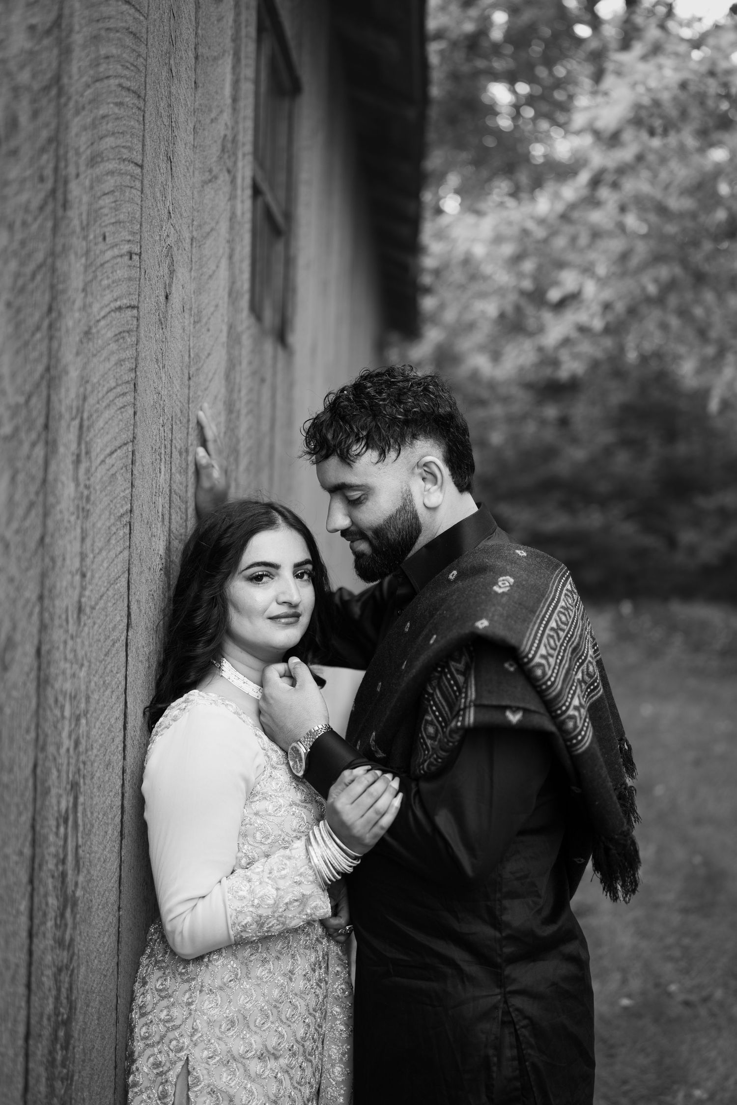 A romantic couple poses intimately against a stone column in a series of black and white photos.