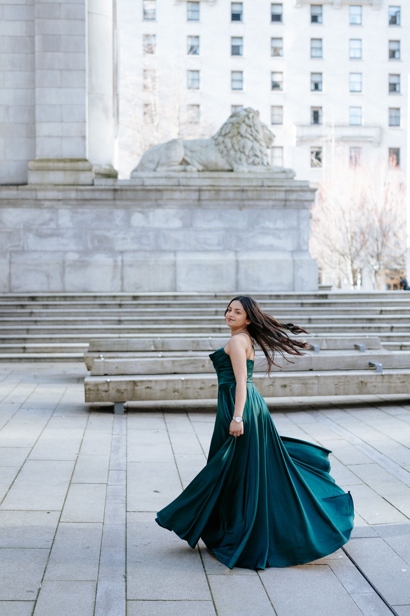 A sequence of photos showing a flowing emerald green gown twirling gracefully on stone steps of a grand building.