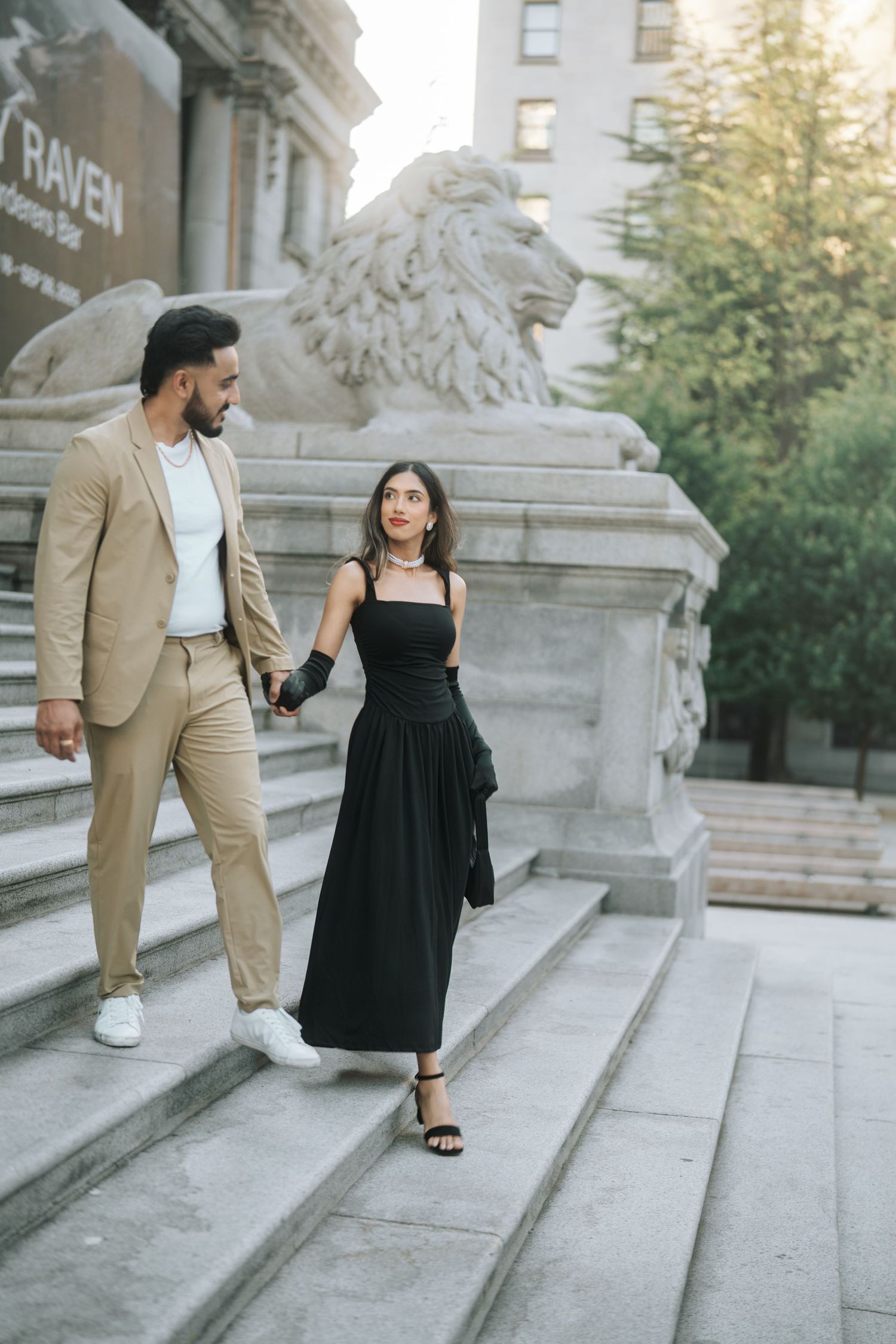 A couple in coordinated formal attire poses on stone steps during a romantic photoshoot at sunset.