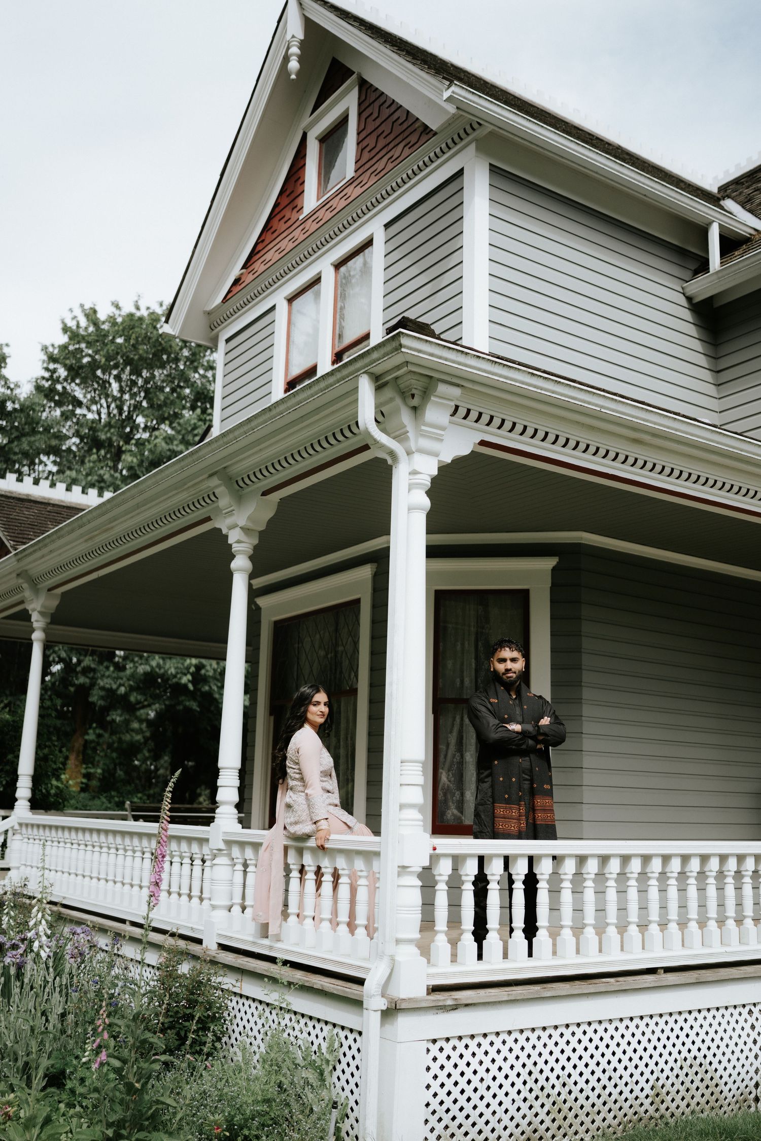 A classic white Victorian-style house with an ornate wraparound porch and decorative railings.