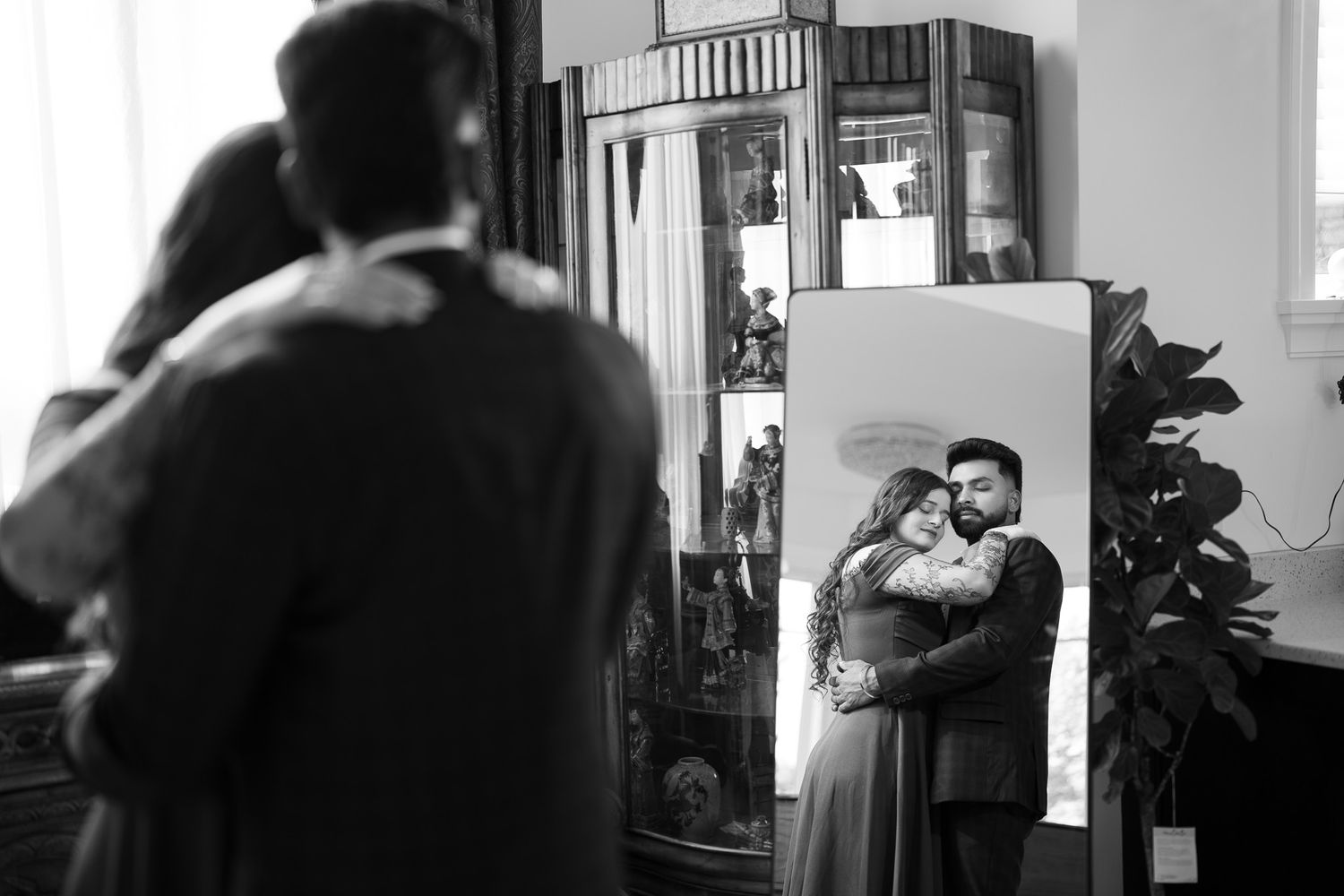 Couple embracing reflected in ornate mirror captured in black and white photography.