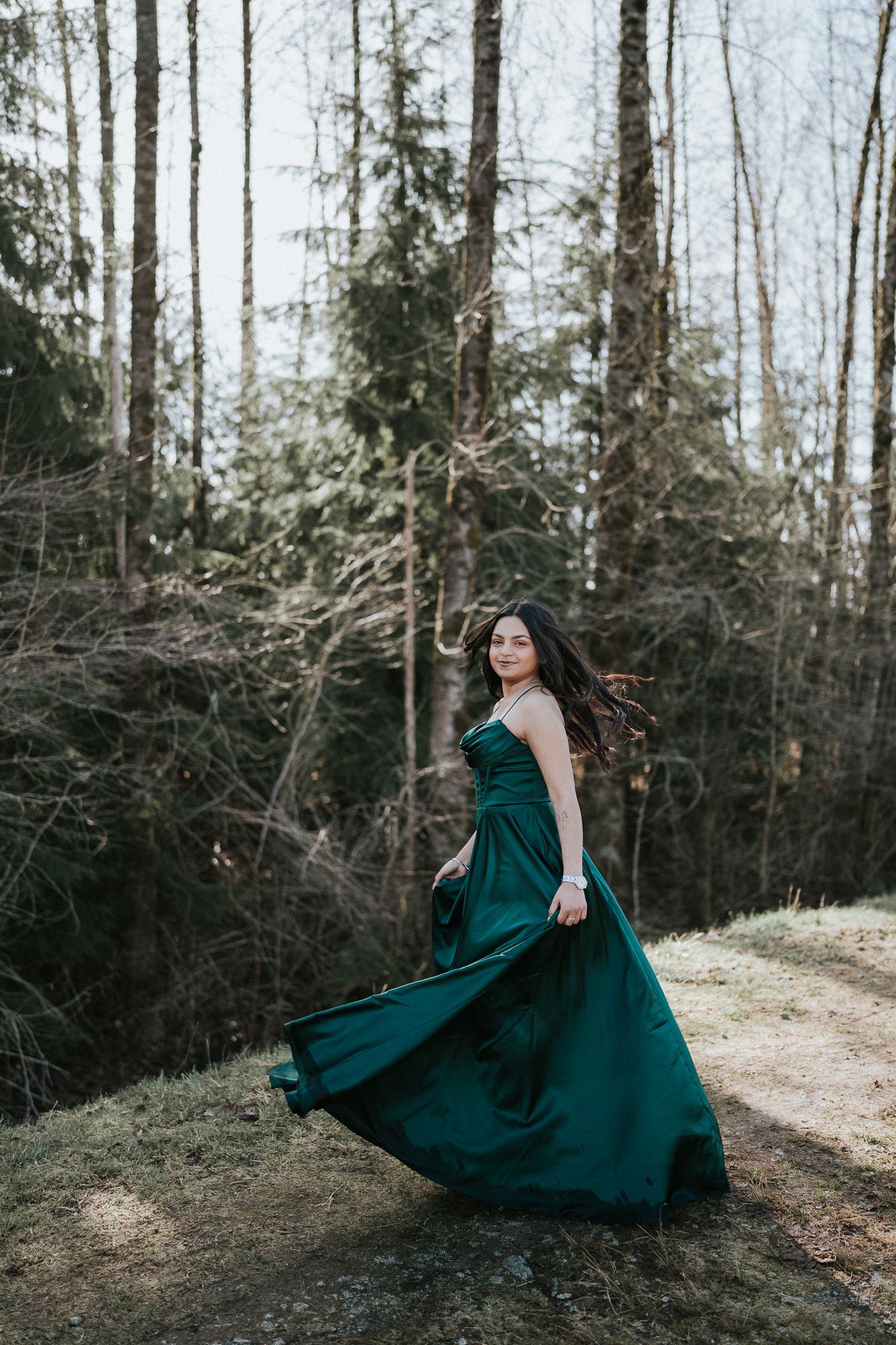 A flowing emerald green dress twirls gracefully through a misty forest setting in winter.