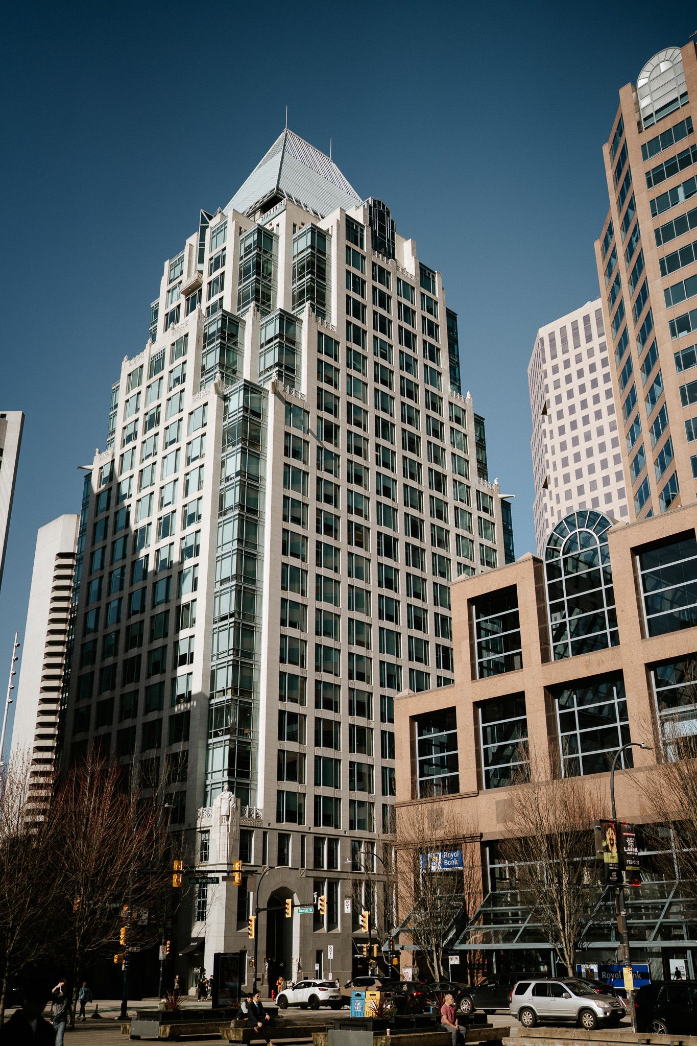 Modern glass and steel skyscraper with distinctive pyramid top rises against blue sky in downtown business district.