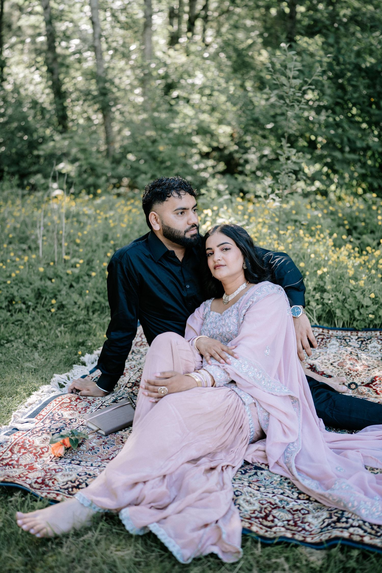 Romantic outdoor portrait on blanket with pink flowing dress and natural backdrop.