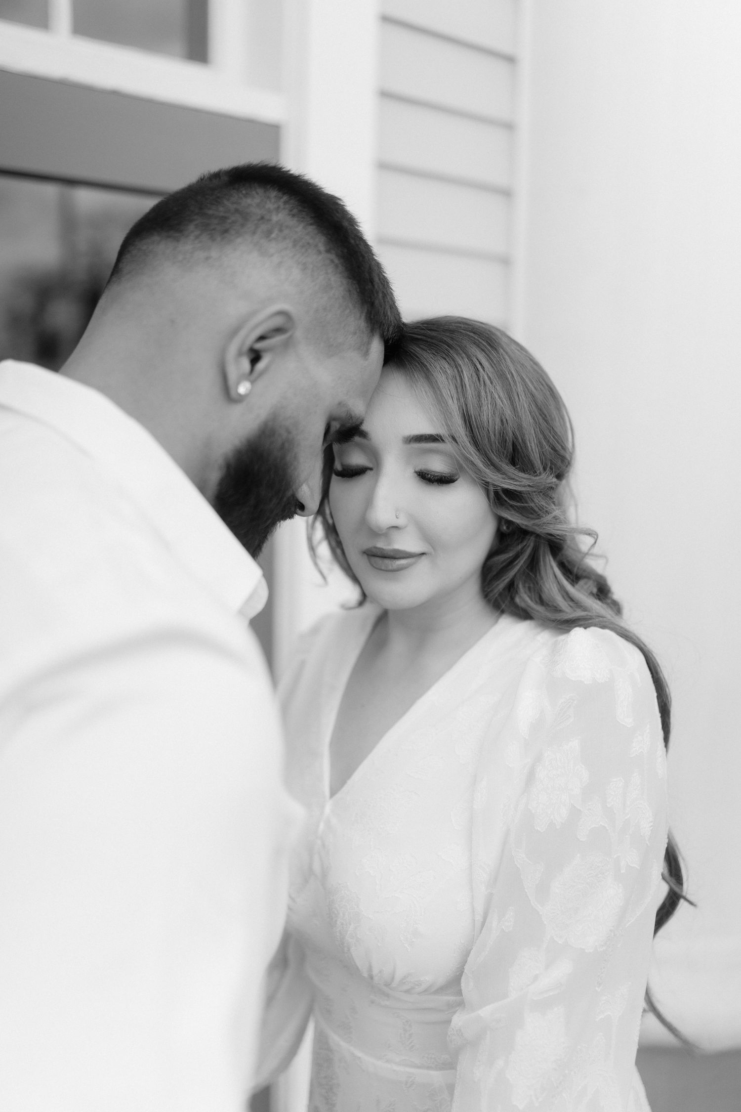 Intimate black and white portrait of a couple in white clothing.