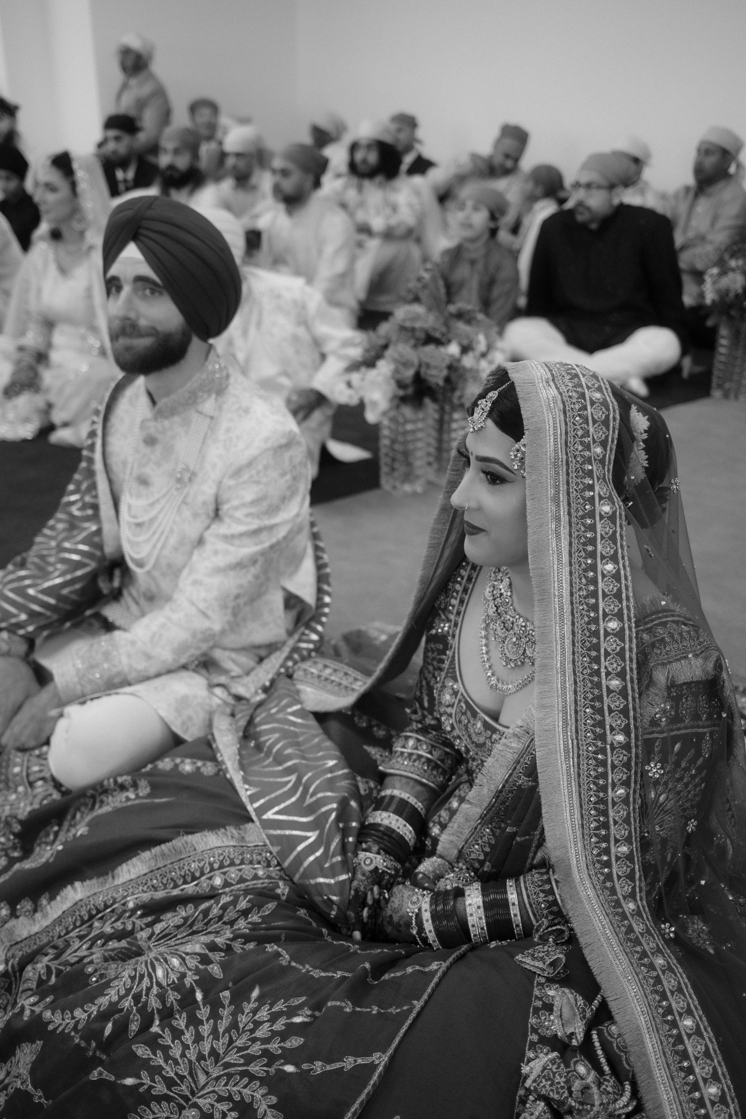 Black and white photo of a Sikh bride and groom sitting during their traditional Anand Karaj wedding ceremony.