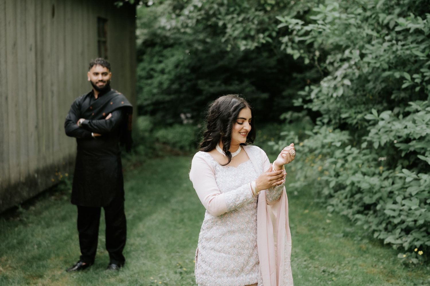 Couple poses together in an outdoor setting with lush greenery.