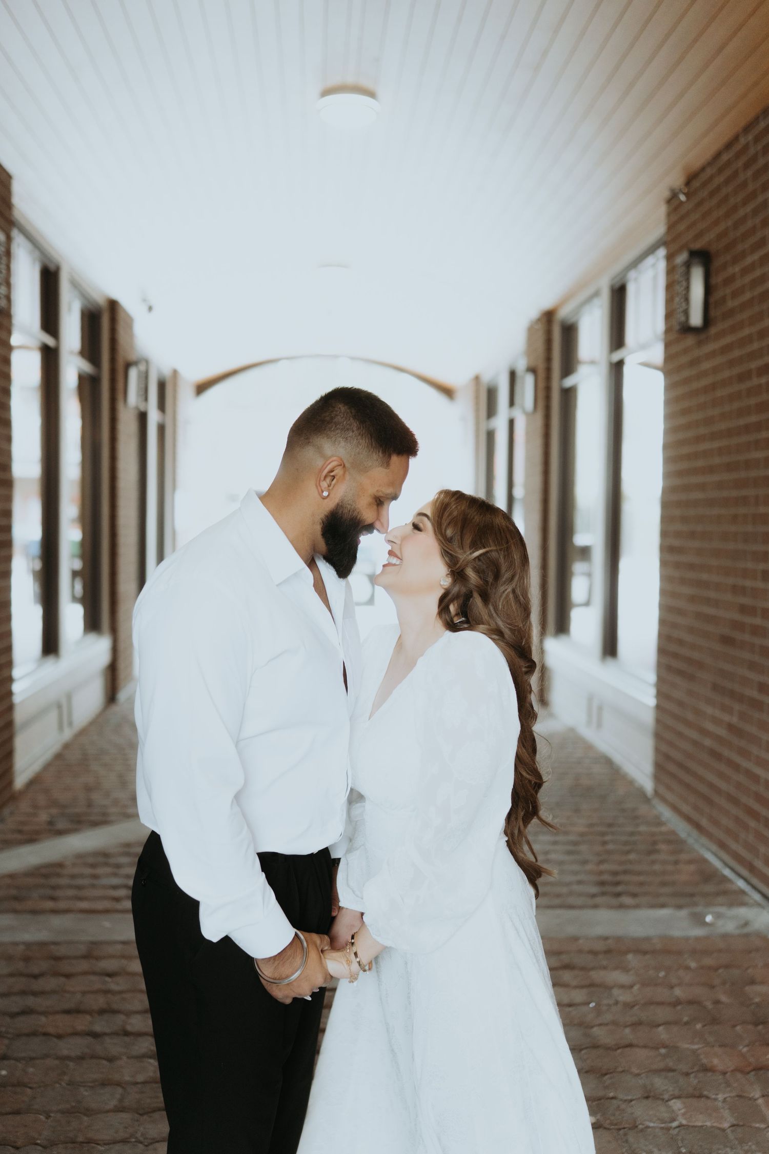 A couple shares romantic moments in a brick hallway with white decor.