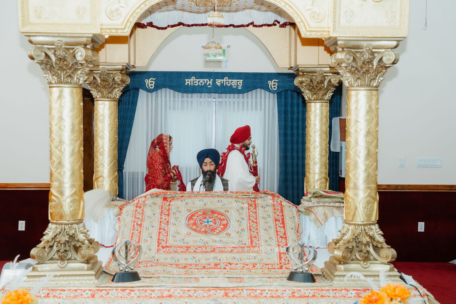 Ornate white and gold temple interior with decorative pillars and archways during a ceremony.