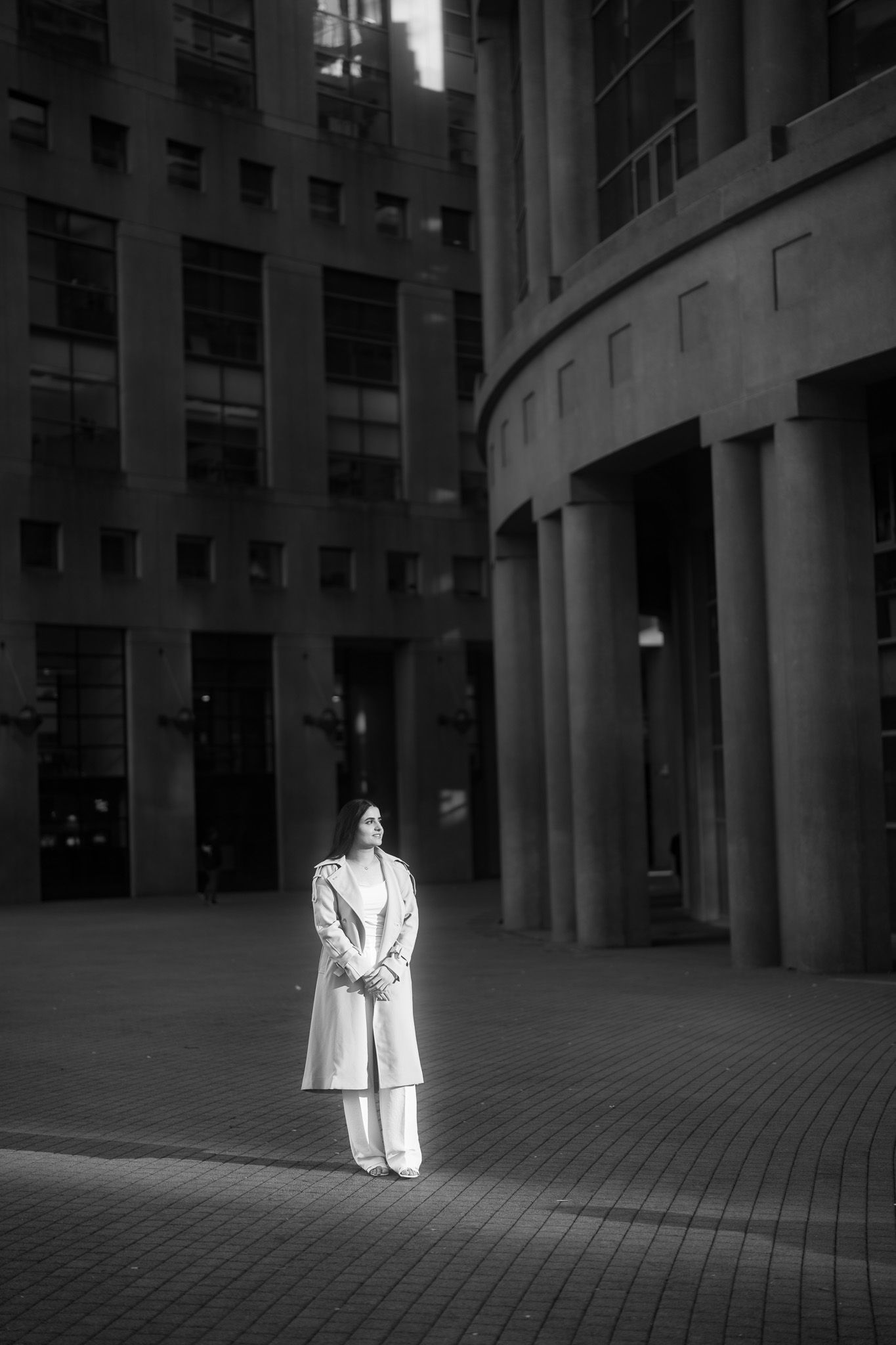 A sequence of black and white photos showing a person in a white coat standing in an empty architectural space.