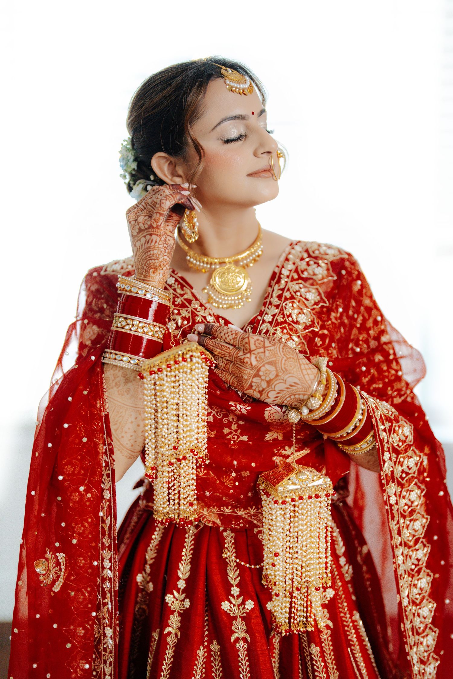 Traditional South Asian bridal attire featuring intricate gold jewelry and embroidered red lehenga details.