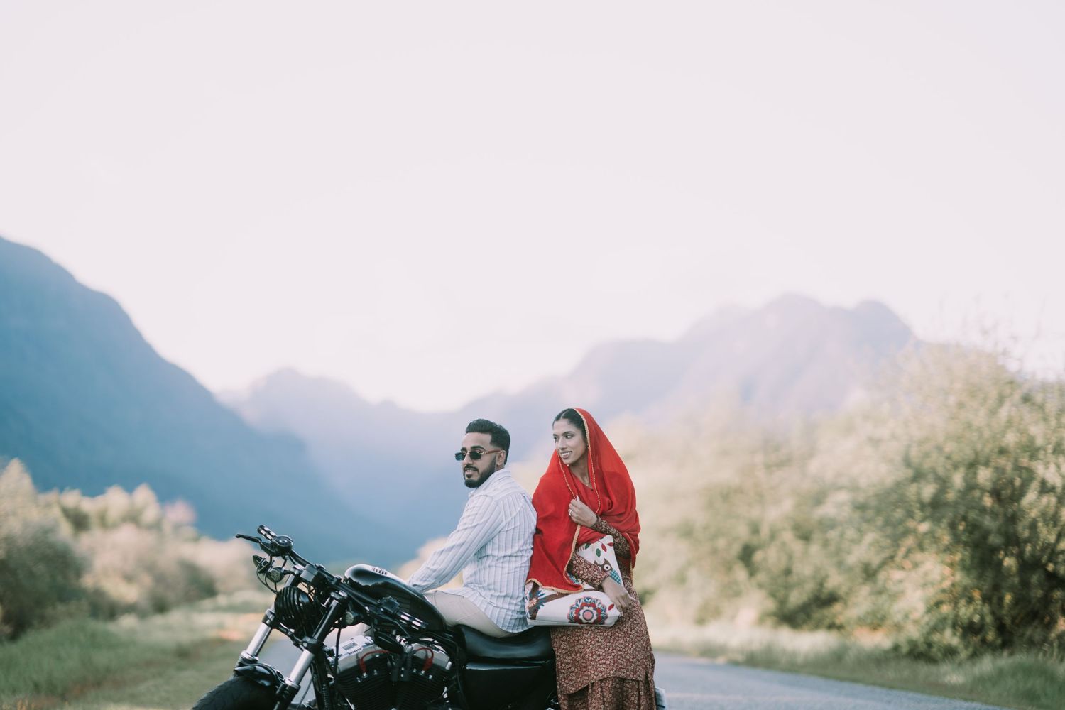 A group of motorcyclists ride through scenic mountain roads during a misty sunset adventure.