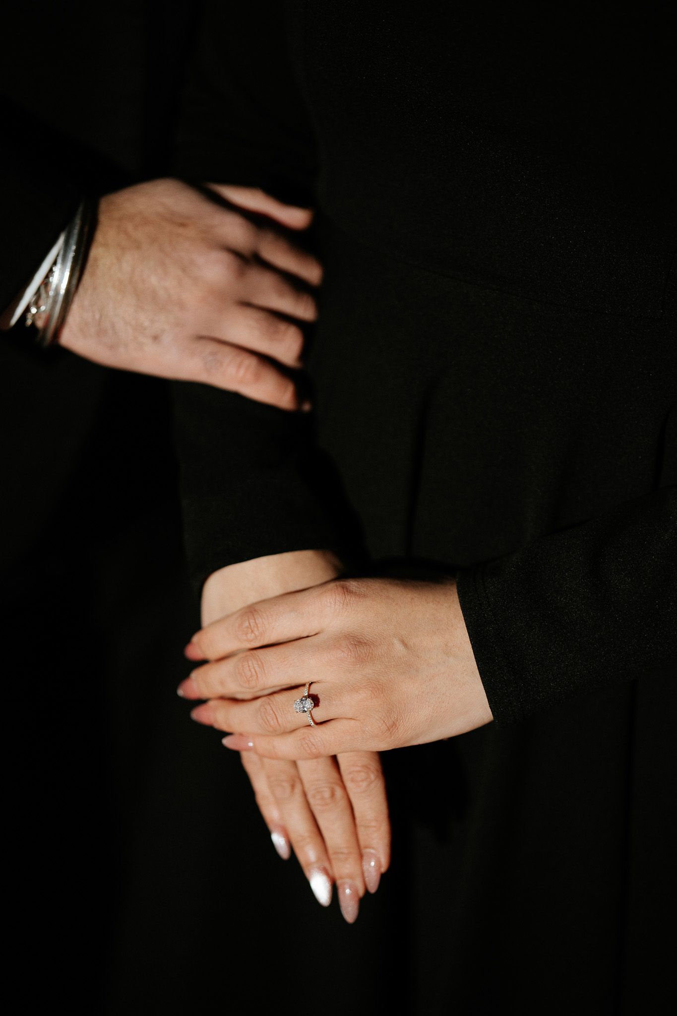 Close-up photos of hands with white manicured nails and a sapphire ring against a dark background.