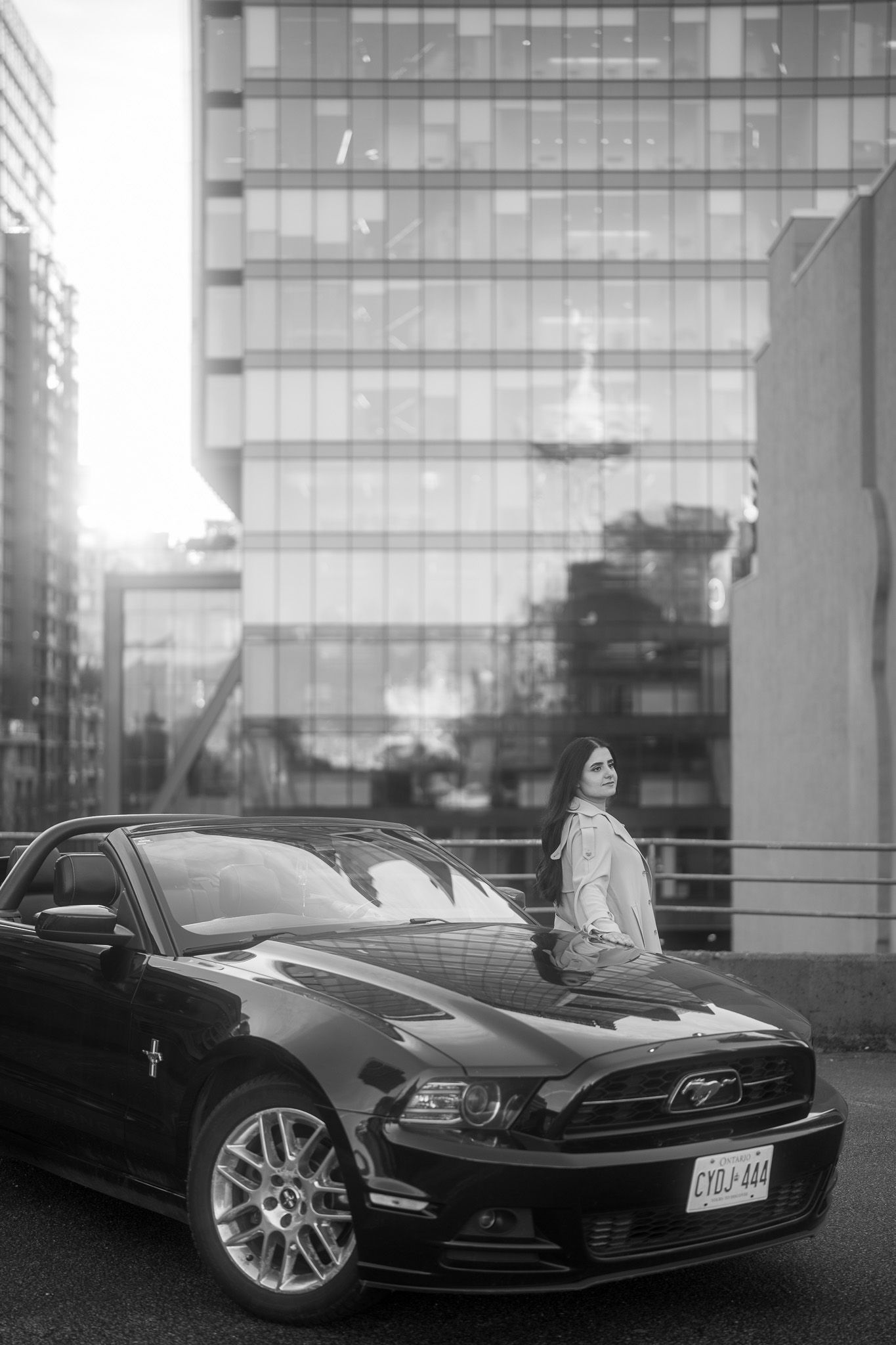 Black Ford Mustang GT sports car shown from multiple angles in front of a modern glass building exterior.