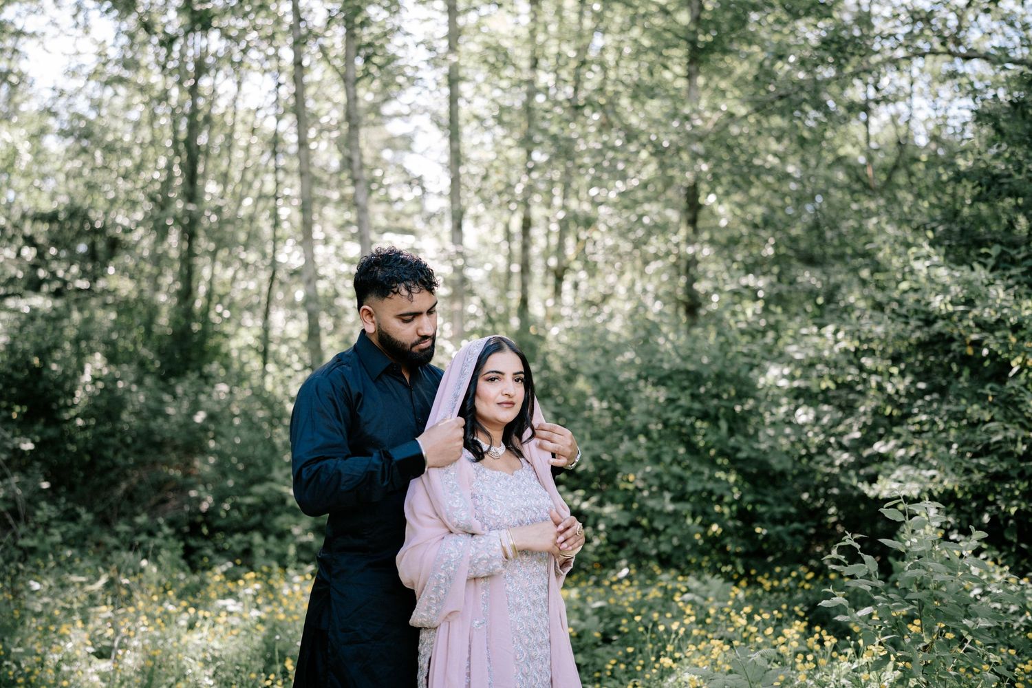 A couple shares an intimate moment during their outdoor photoshoot in a wooded setting.