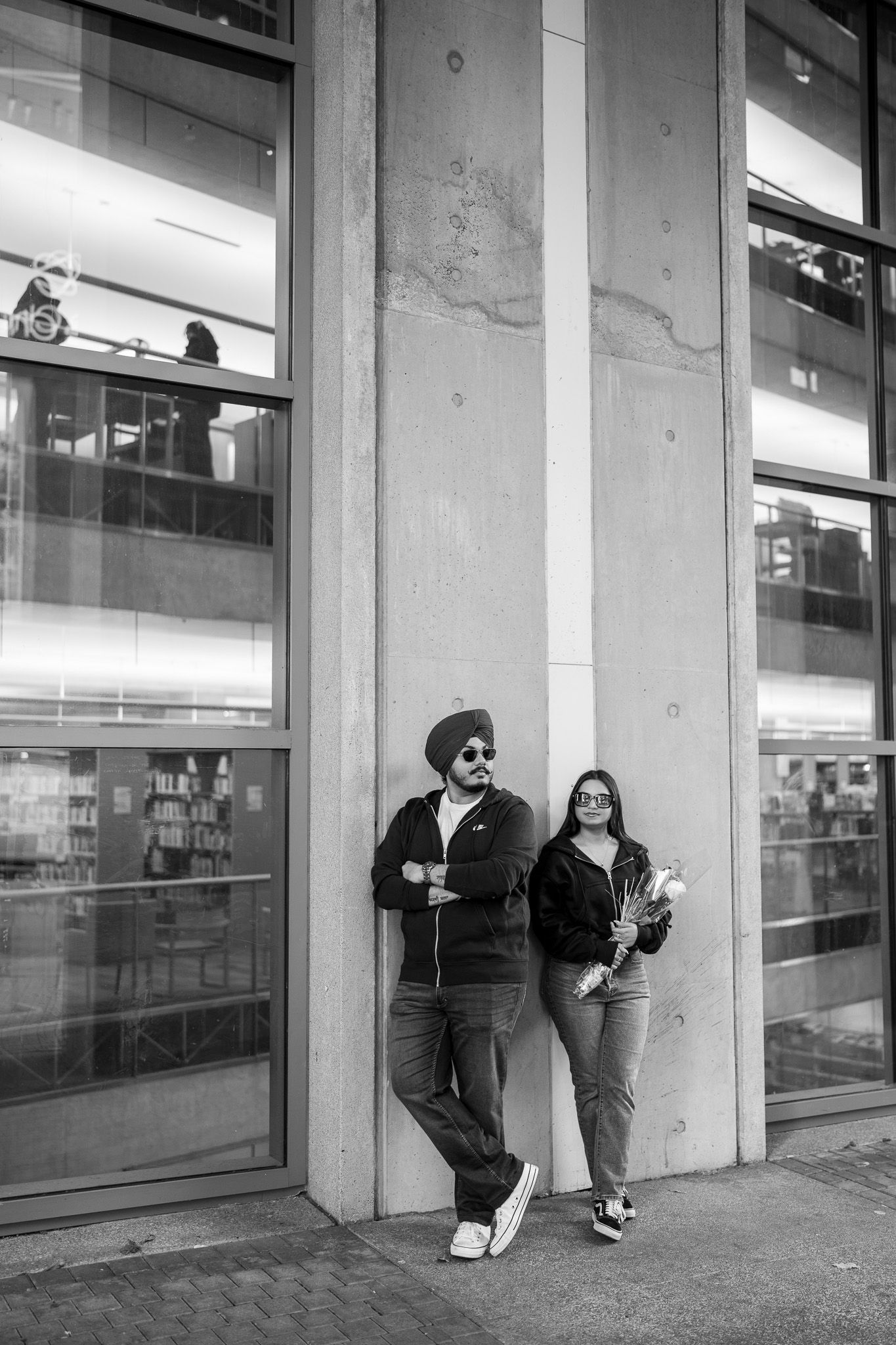 A sequence of black and white photos showing two people playfully running and hiding behind a building wall.