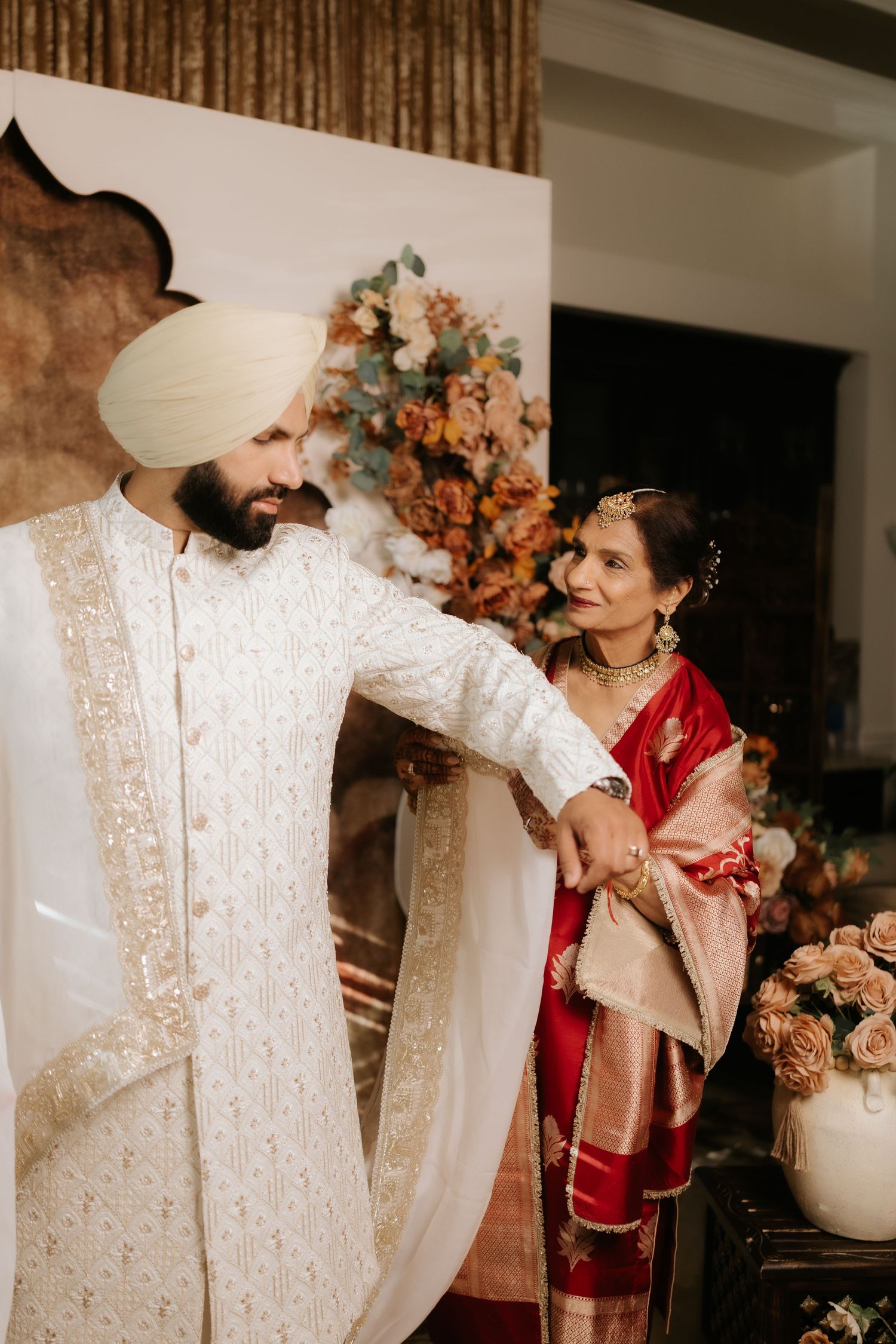 Sikh groom in white sherwani and turban with bride in red saree at traditional Indian wedding ceremony.