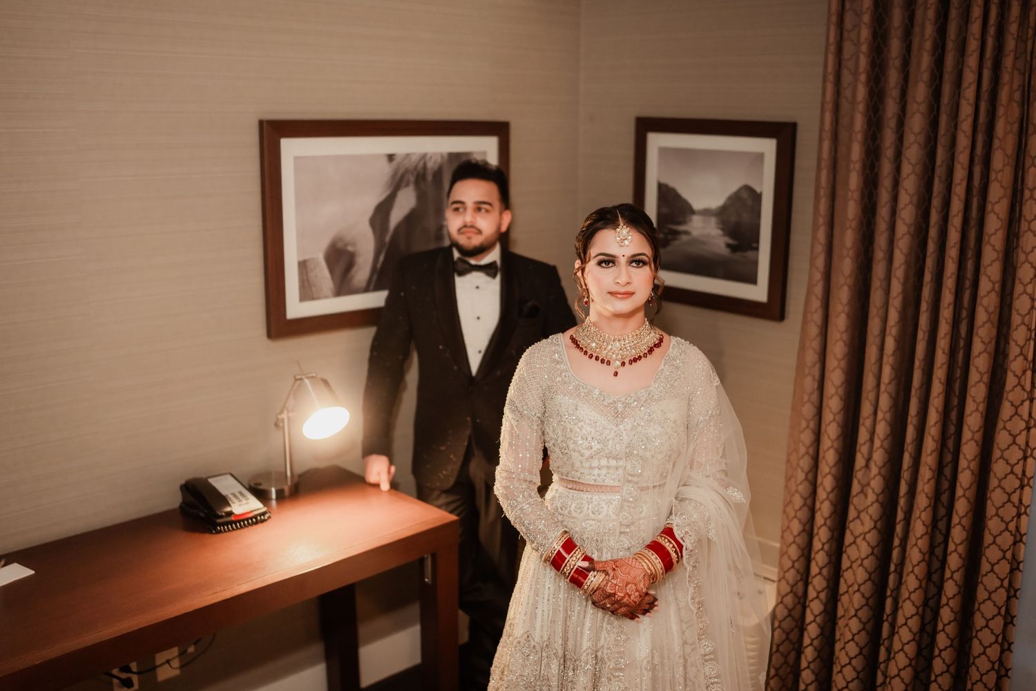 A couple shares an intimate moment in a hotel room decorated with traditional wedding decor.